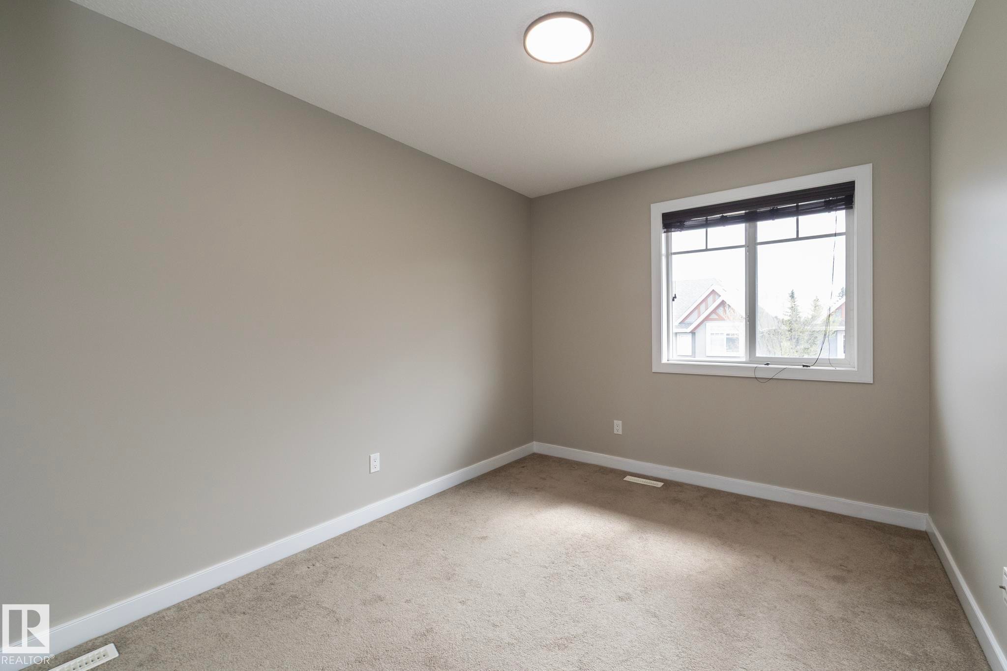 Carpeted room with a double-pane window, white trim, and a flush-mount ceiling light - 117 Callaghan Drive Sw, Edmonton, AB - Indoor Photo Showing Other Room