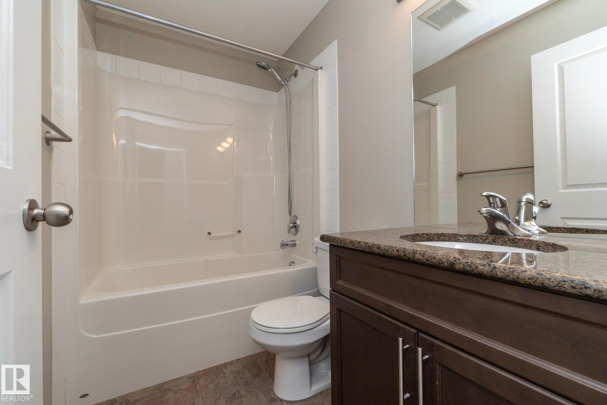 Bathroom featuring a dark wood-finish vanity with a stone-look countertop, integrated sink, and chrome faucet - 117 Callaghan Drive Sw, Edmonton, AB - Indoor Photo Showing Bathroom