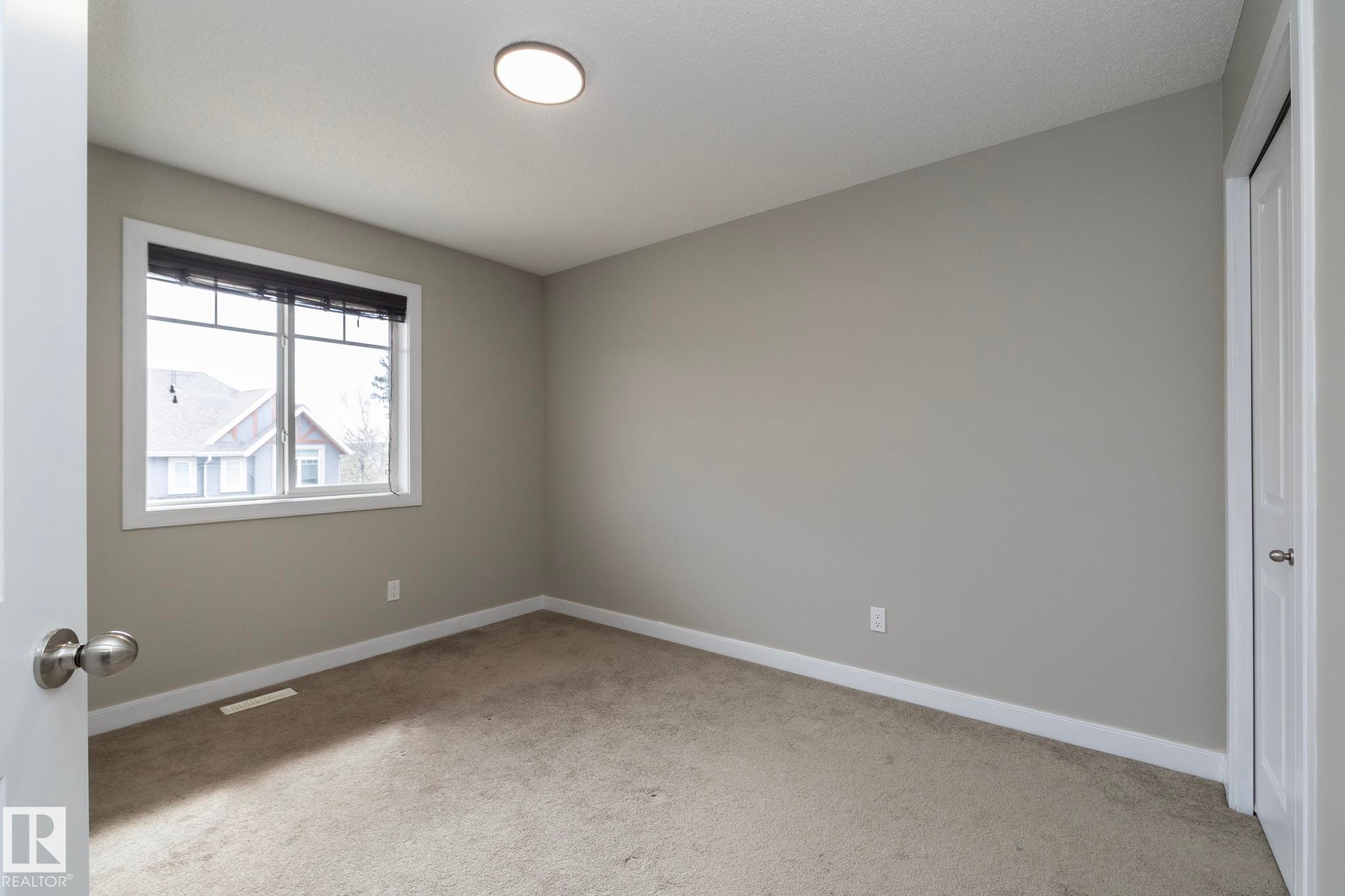 Neutral-toned room featuring a single window with blinds, light gray wall paint, and beige carpet flooring - 117 Callaghan Drive Sw, Edmonton, AB - Indoor Photo Showing Other Room
