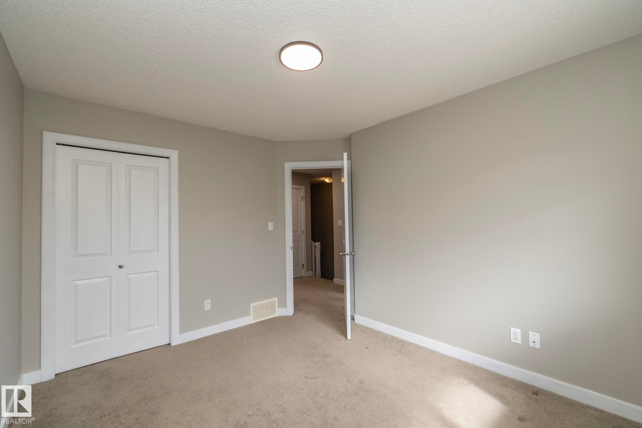 Carpeted room featuring light gray walls, white baseboards, and a bi-fold closet door - 117 Callaghan Drive Sw, Edmonton, AB - Indoor