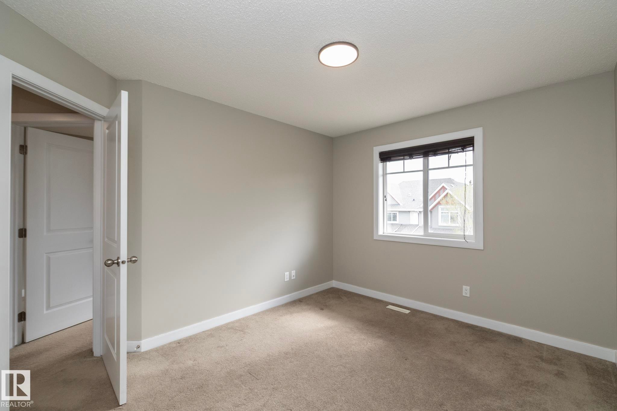 Neutral tone wall paint with white trim, carpeting, a single window with blinds, and an overhead flush-mount light fixture - 117 Callaghan Drive Sw, Edmonton, AB - Indoor Photo Showing Other Room