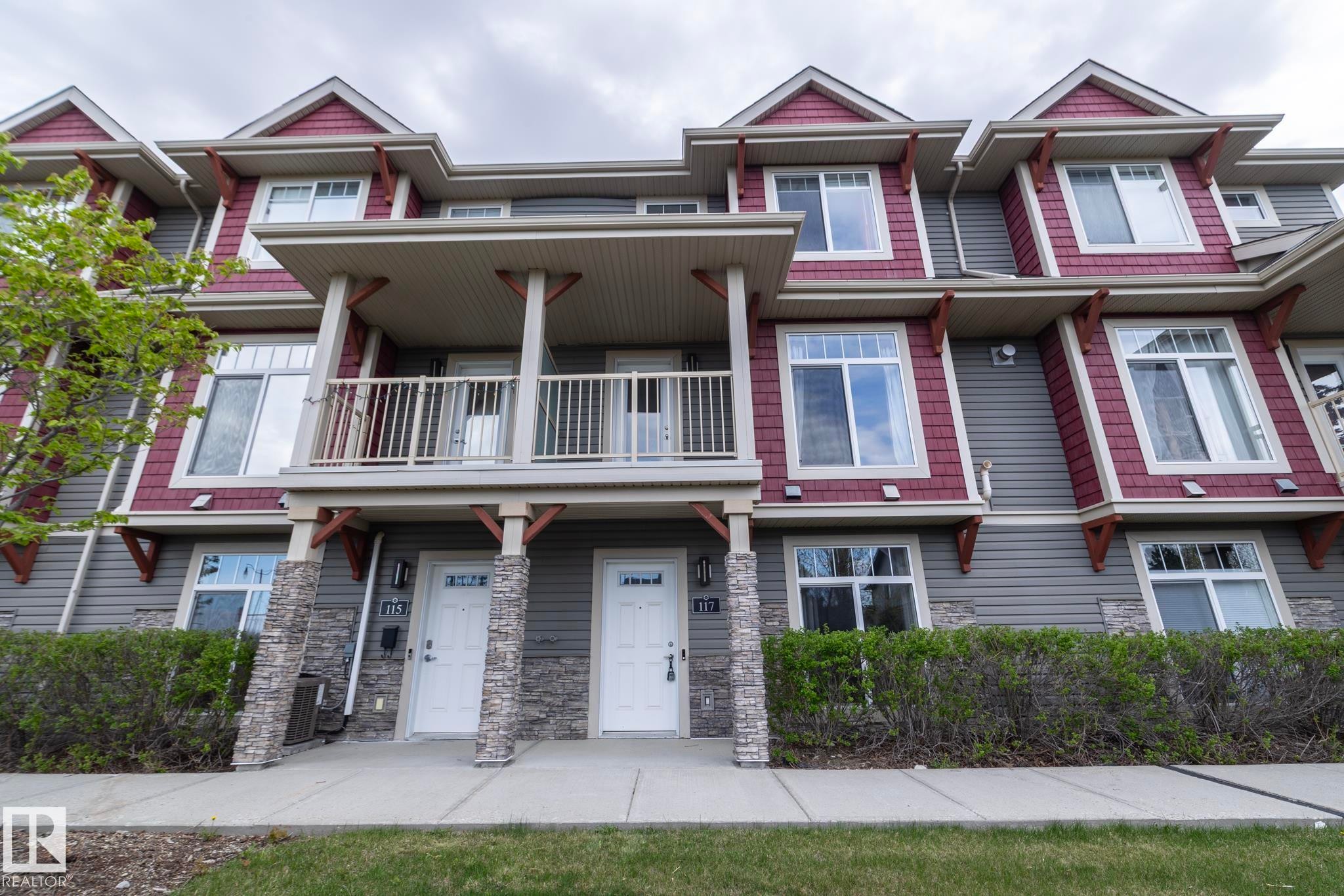 Townhome exterior featuring gray horizontal siding and red shake accents - 117 Callaghan Drive Sw, Edmonton, AB - Outdoor With Facade