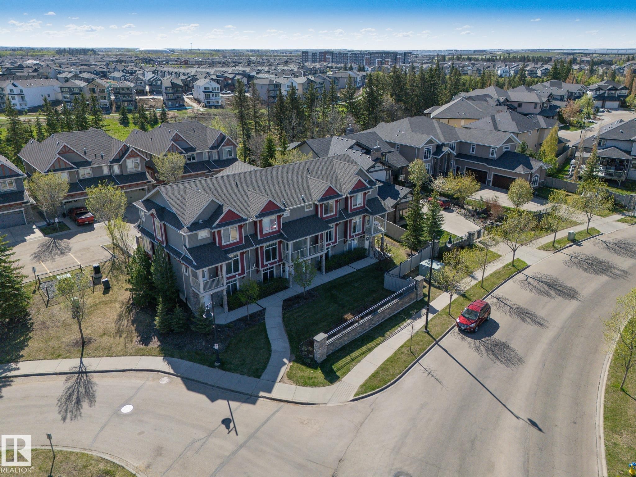 Residential property featuring multiple structures with dark shingle roofs, grey siding, and red trim accents - 117 Callaghan Drive Sw, Edmonton, AB - Outdoor With View