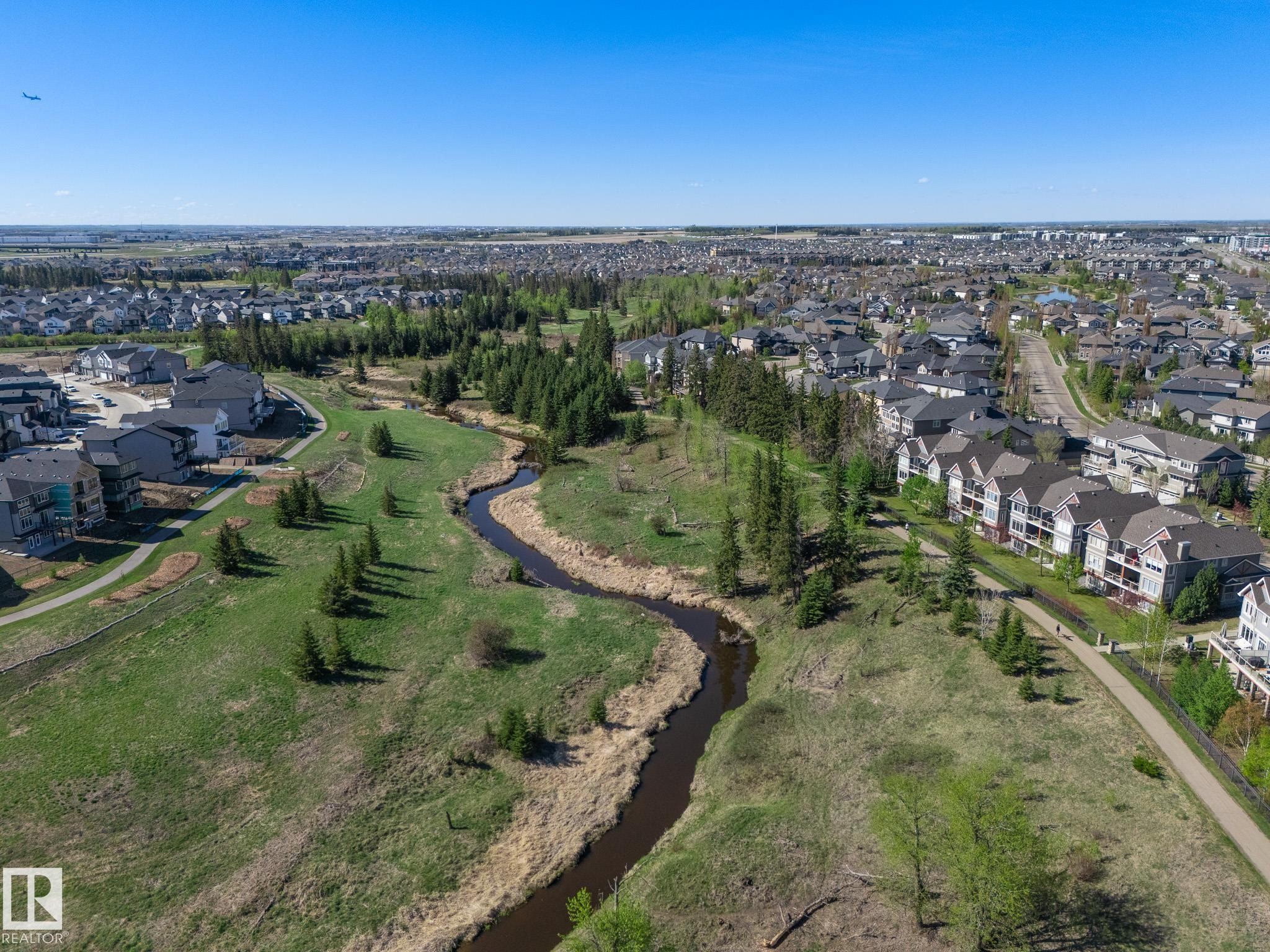 Expansive green space featuring a winding creek, mature trees, and paved pedestrian paths - 117 Callaghan Drive Sw, Edmonton, AB - Outdoor With View
