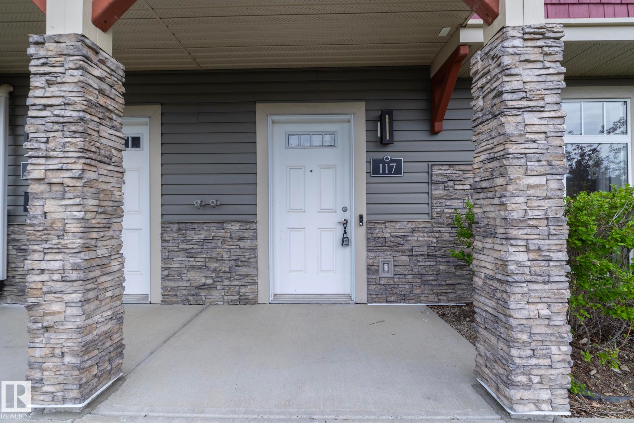 Covered entry with stone veneer columns, horizontal siding, and an overhead light fixture - 117 Callaghan Drive Sw, Edmonton, AB - Outdoor