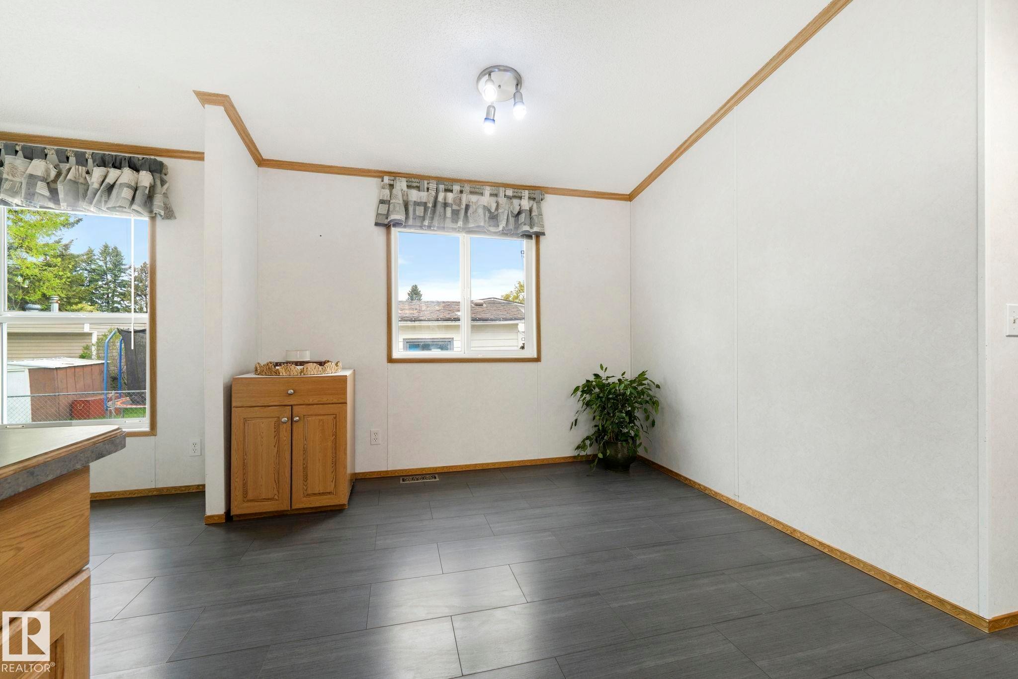 Spacious interior room featuring dark wood-finish flooring and two large windows - 49 Rim Road Nw, Edmonton, AB - Indoor Photo Showing Other Room