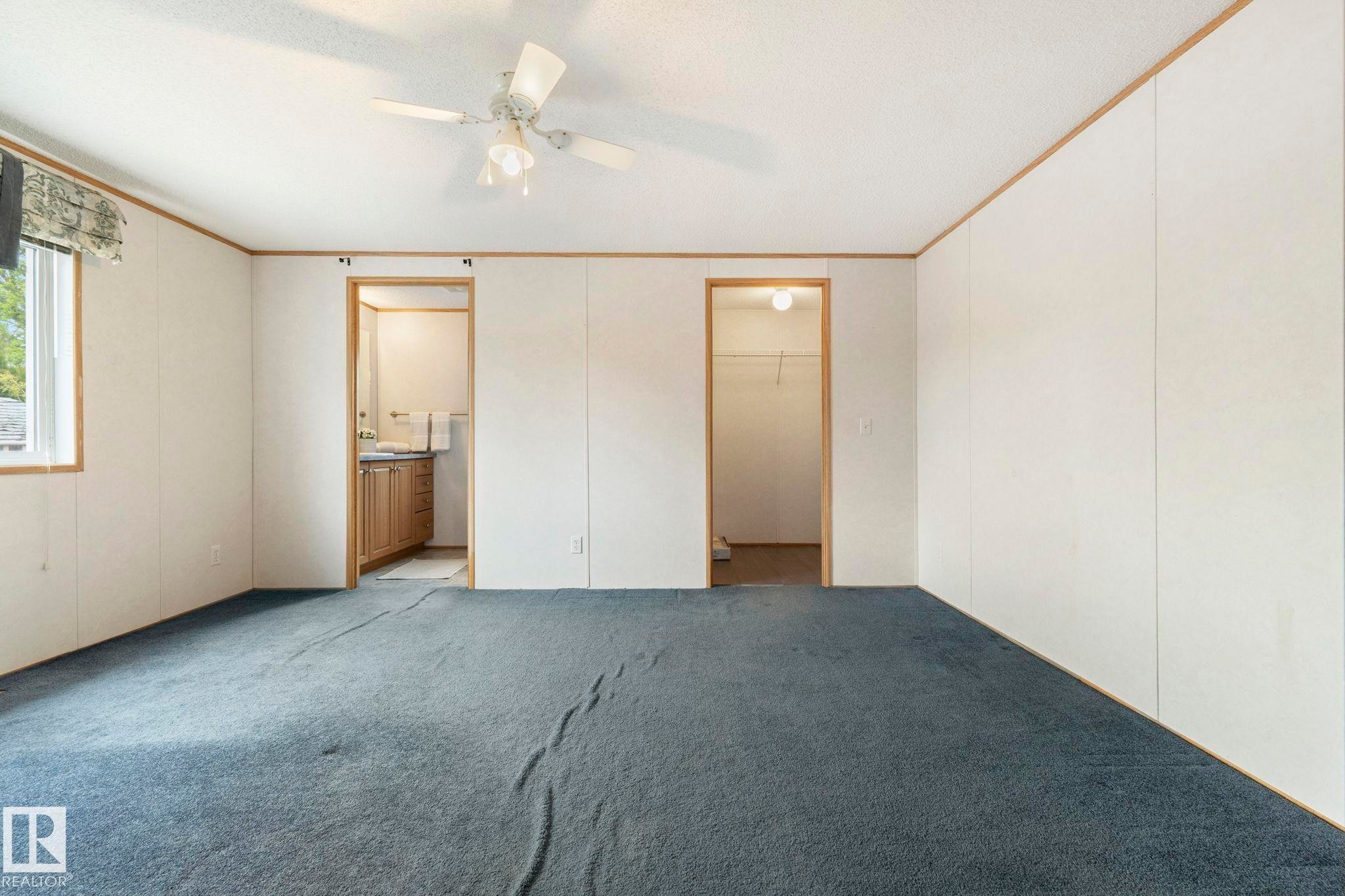 Spacious interior with blue carpeting, white paneling, and wood-trim accents - 49 Rim Road Nw, Edmonton, AB - Indoor Photo Showing Other Room