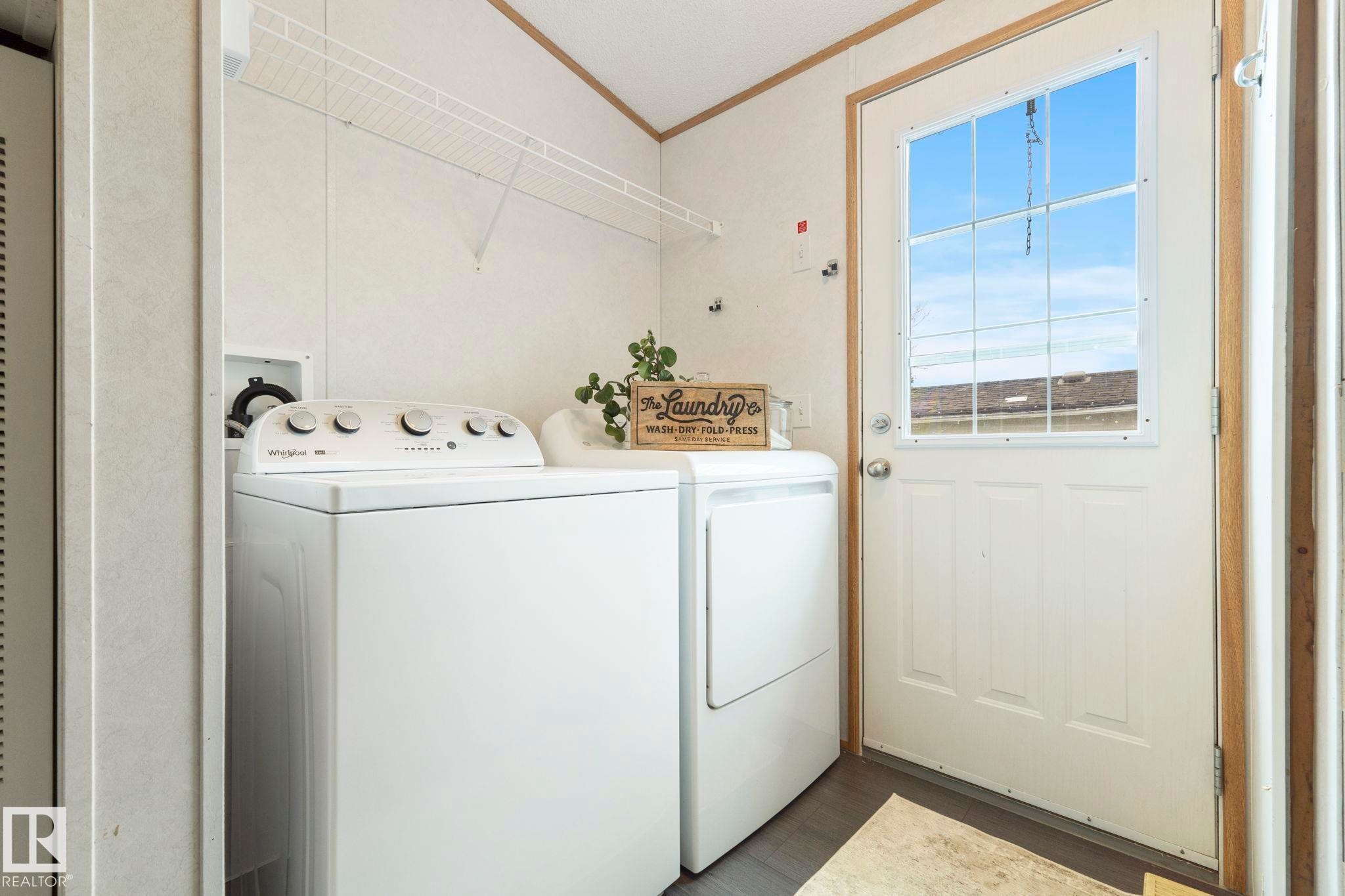 Dedicated laundry area featuring wire shelving, durable flooring, and direct exterior access - 49 Rim Road Nw, Edmonton, AB - Indoor Photo Showing Laundry Room