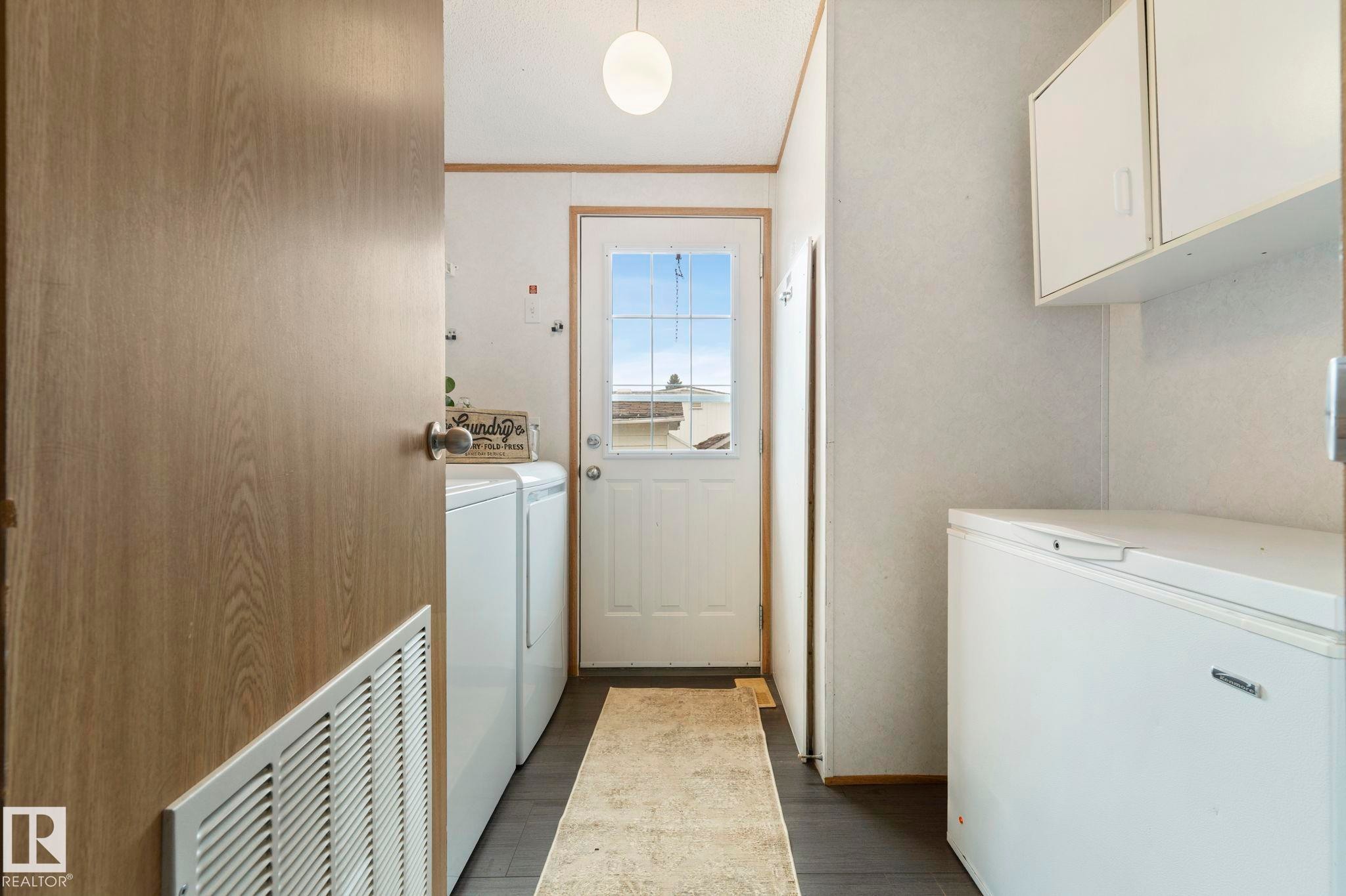 Mudroom area featuring a white paneled door with window panes, white upper cabinetry, and dark-finish flooring - 49 Rim Road Nw, Edmonton, AB - Indoor