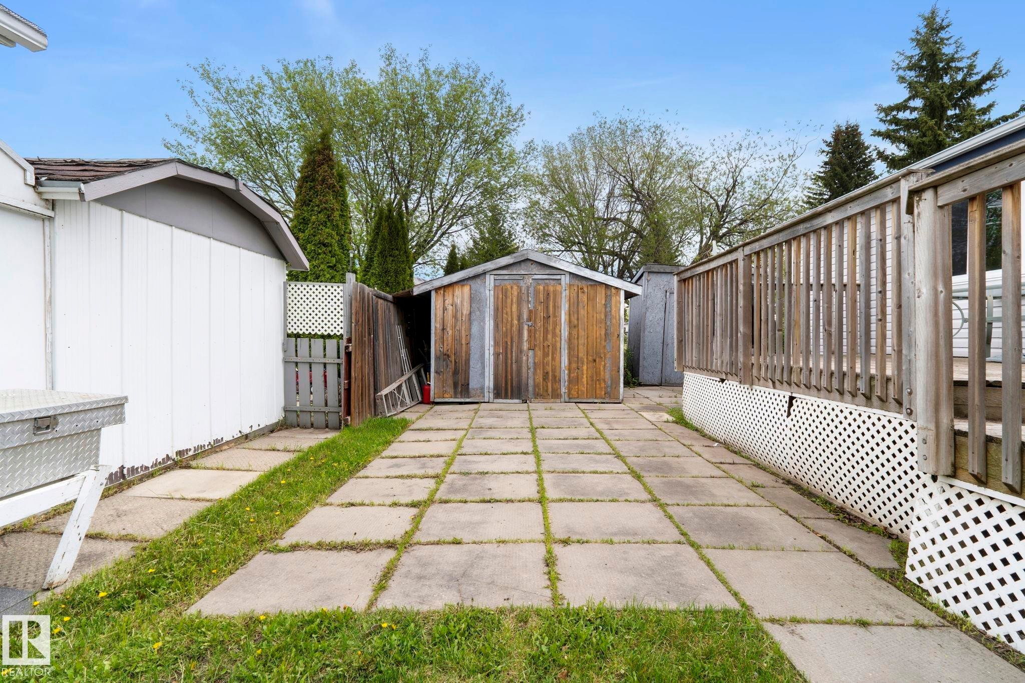 Paved patio area featuring concrete stepping stones, a wooden storage shed, and a wooden privacy fence - 49 Rim Road Nw, Edmonton, AB - Outdoor With Exterior