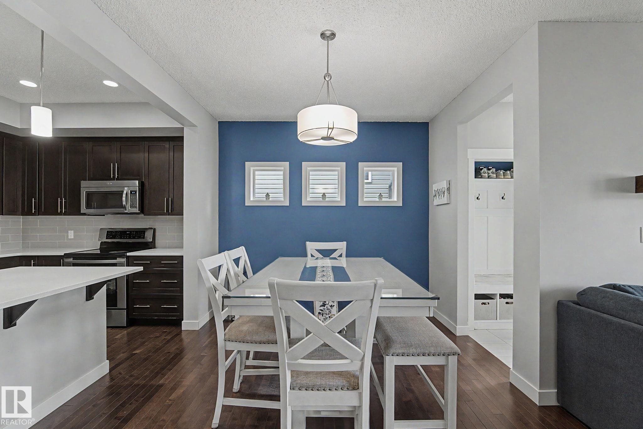 Open-concept dining area featuring a distinct accent wall and wood-finish flooring - 18144 76 Street Nw, Edmonton, AB - Indoor