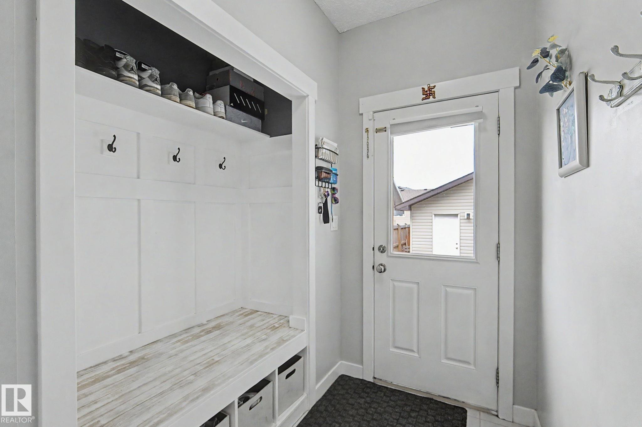 Entryway featuring built-in storage with a wood-finish bench, coat hooks, and a top shelf - 18144 76 Street Nw, Edmonton, AB - Indoor Photo Showing Other Room