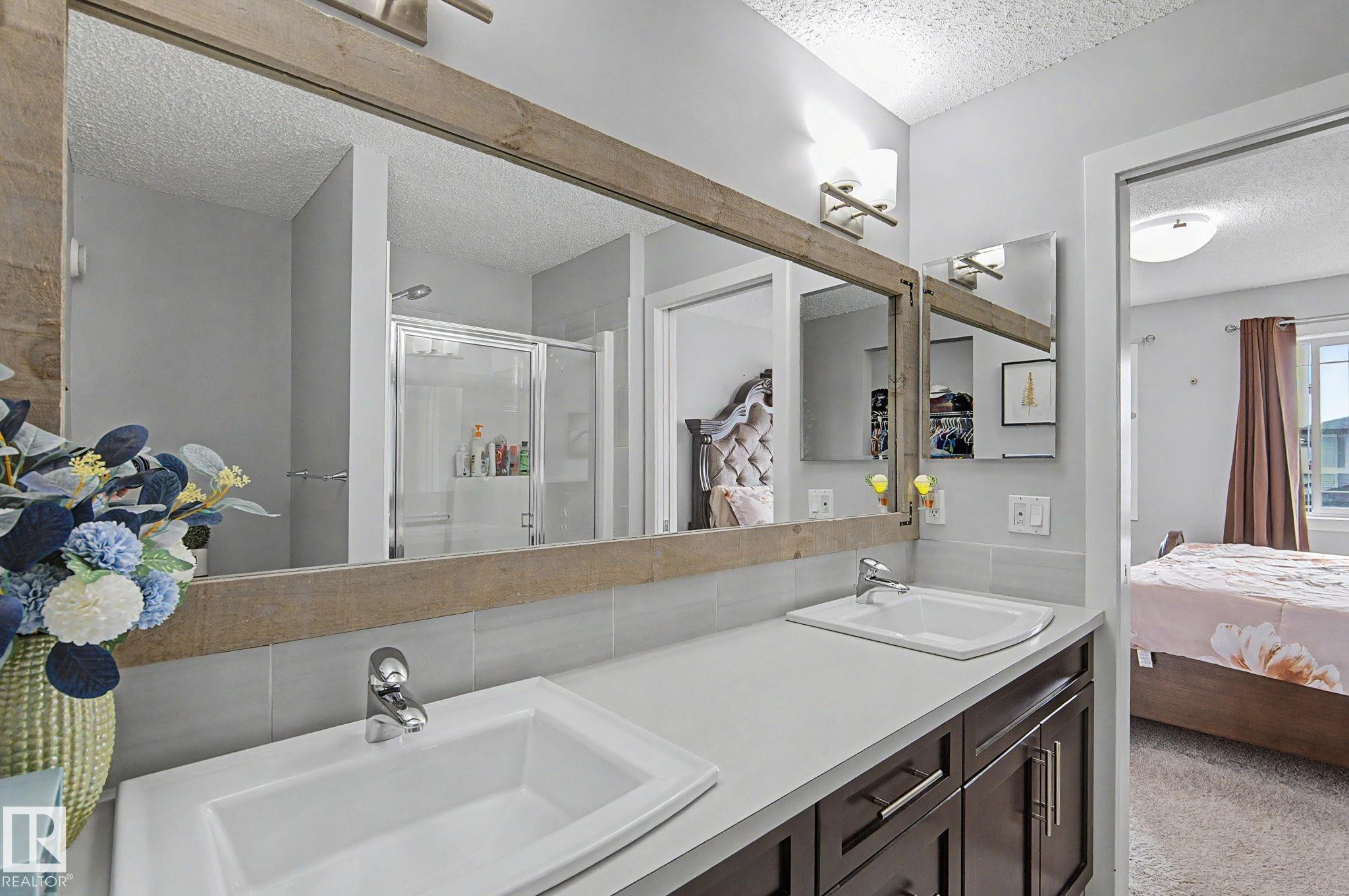 Double vanity featuring white rectangular sinks, chrome faucets, a light-colored countertop, and dark wood-finish cabinetry - 18144 76 Street Nw, Edmonton, AB - Indoor Photo Showing Bathroom