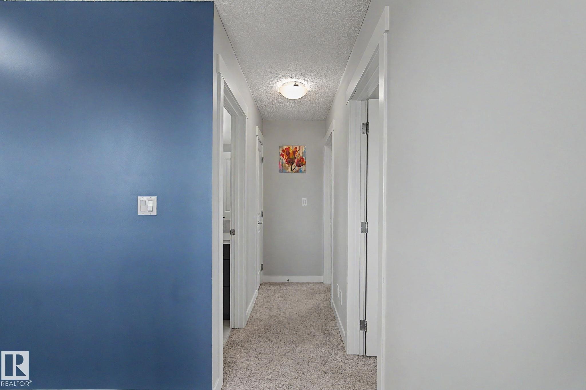 Carpeted hallway with light gray walls and white trim - 18144 76 Street Nw, Edmonton, AB - Indoor Photo Showing Other Room