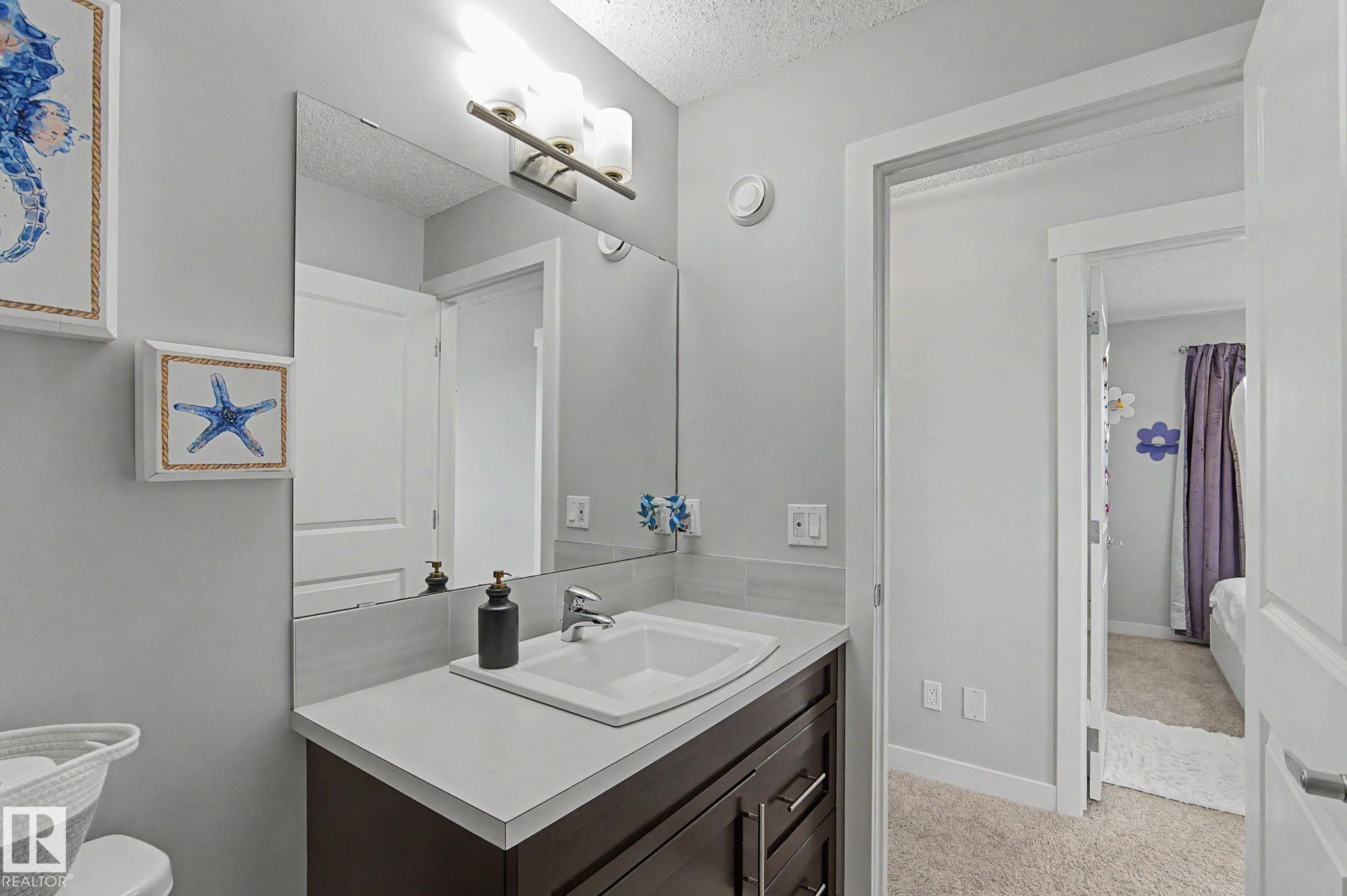Bathroom vanity featuring a rectangular undermount sink, a stone-finish countertop, and a dark wood-finish cabinet with chrome hardware - 18144 76 Street Nw, Edmonton, AB - Indoor Photo Showing Bathroom