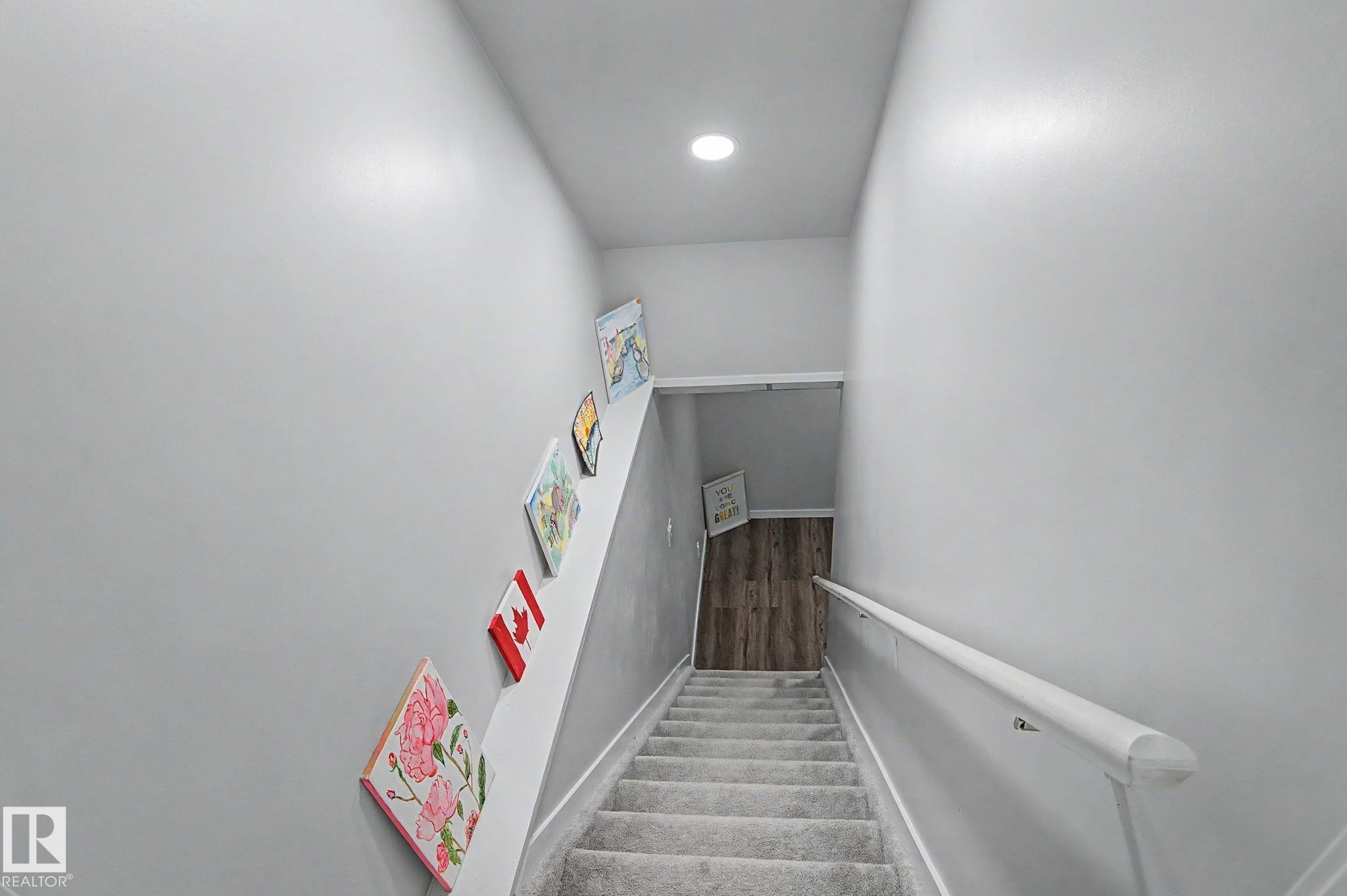 Carpeted staircase with light gray walls, a white handrail, and a recessed ceiling light - 18144 76 Street Nw, Edmonton, AB - Indoor Photo Showing Other Room