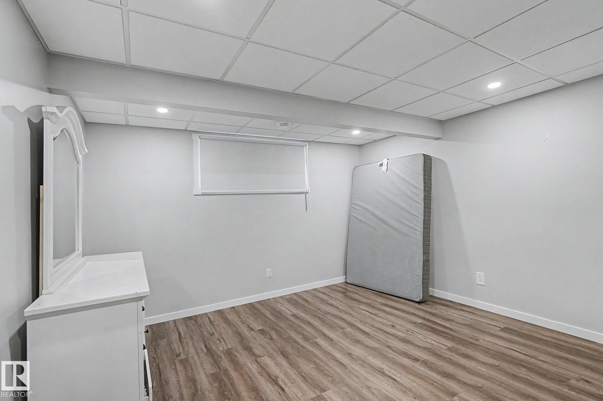 Room featuring wood-finish flooring, recessed lighting, and a drop ceiling - 18144 76 Street Nw, Edmonton, AB - Indoor Photo Showing Other Room