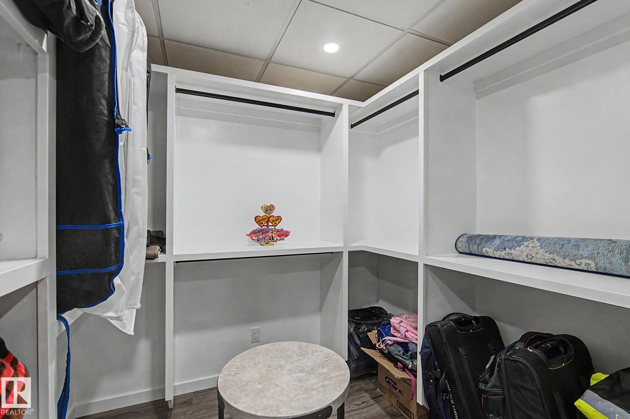 Custom closet system with white shelving, integrated hanging rods, recessed lighting, and wood-finish flooring - 18144 76 Street Nw, Edmonton, AB - Indoor With Storage