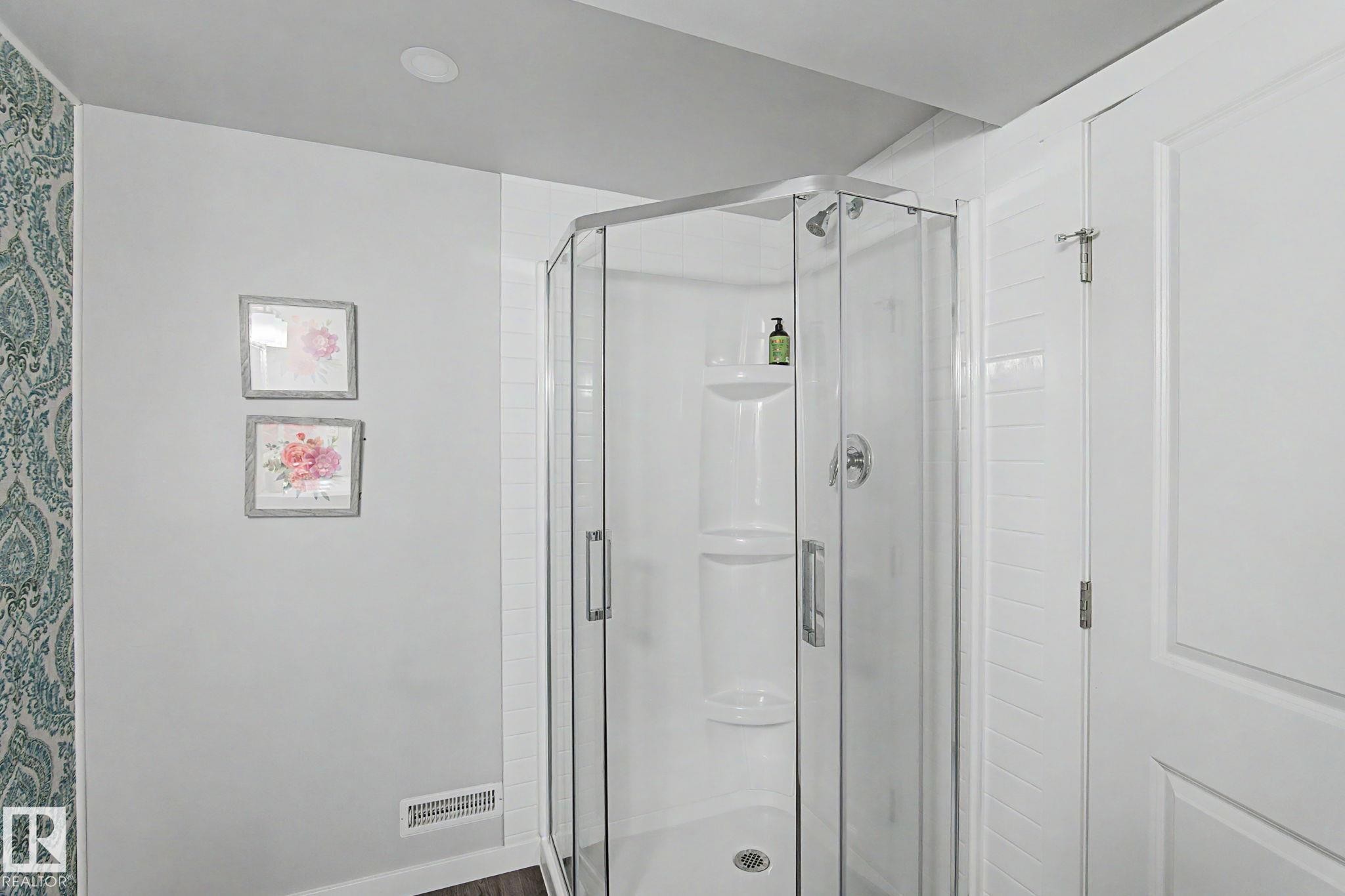 Corner glass-enclosed shower featuring a white base and a built-in shelf - 18144 76 Street Nw, Edmonton, AB - Indoor Photo Showing Bathroom