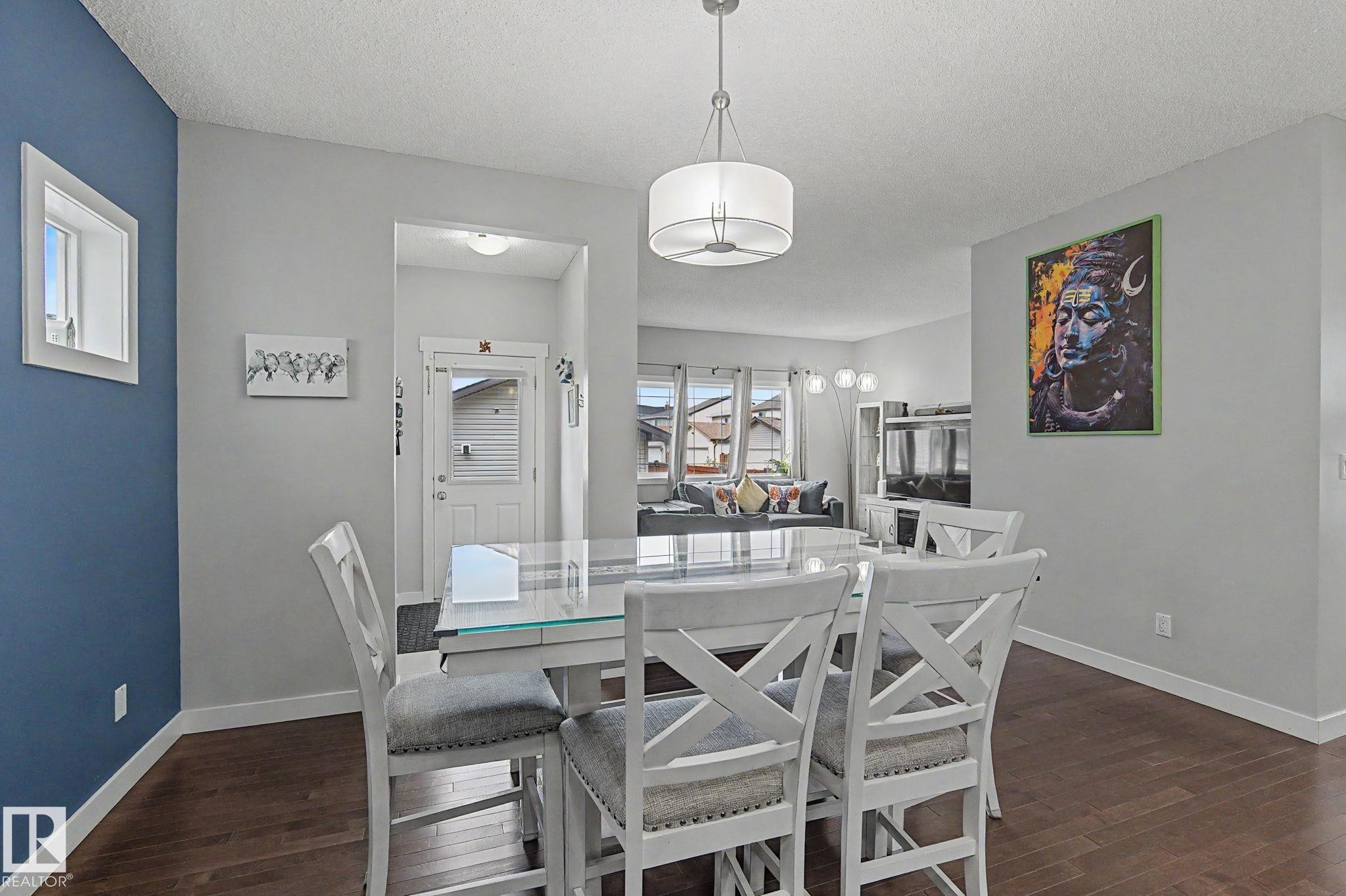 Dining area featuring dark wood-finish flooring, light grey walls, and a contemporary drum pendant light fixture - 18144 76 Street Nw, Edmonton, AB - Indoor Photo Showing Dining Room