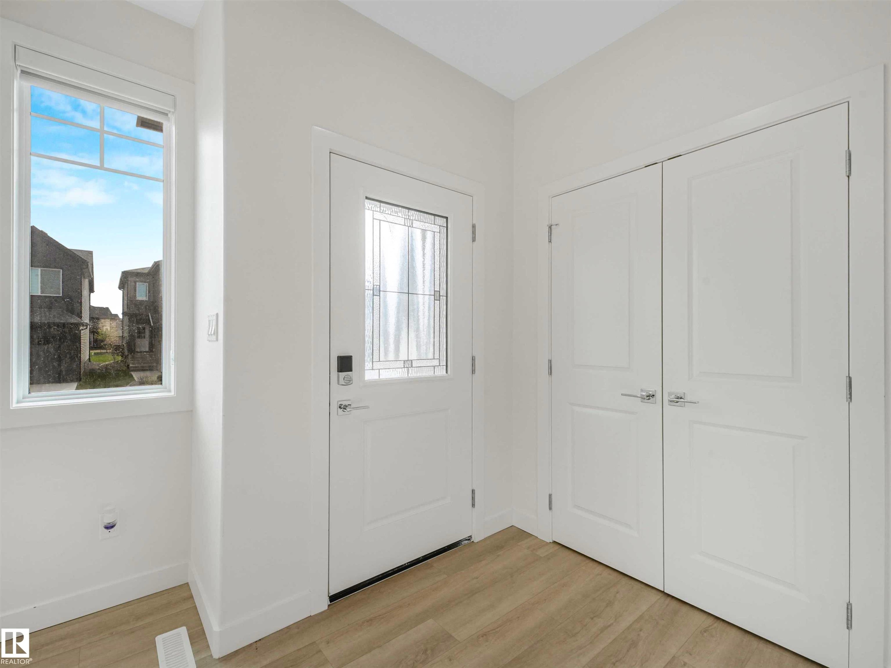 Foyer featuring light wood-finish flooring, white trim, and a white entry door with decorative glass inserts - 1518 Siskin Link Link, Edmonton, AB - Indoor Photo Showing Other Room