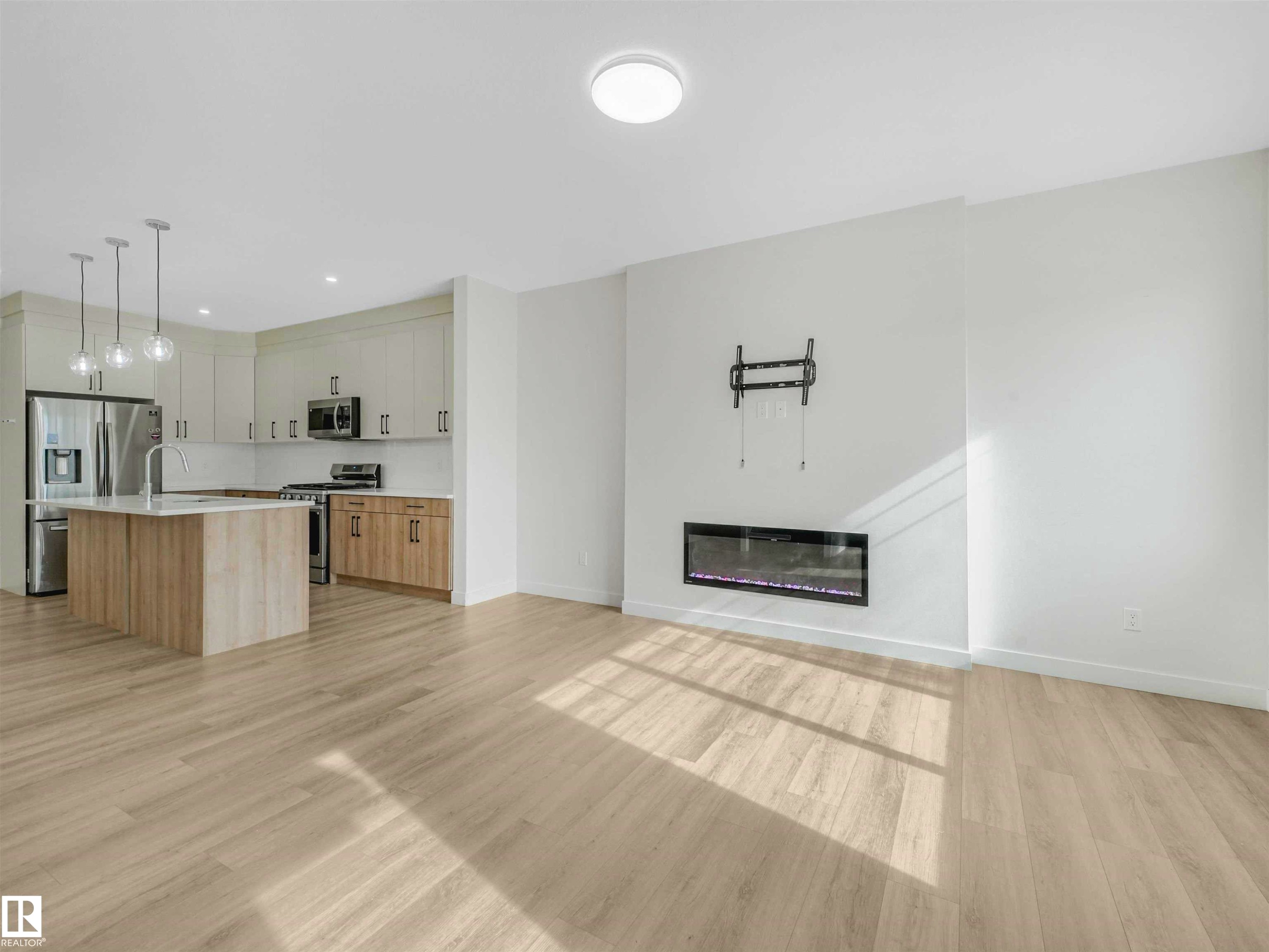 Open-concept living space with light wood-finish flooring - 1518 Siskin Link Link, Edmonton, AB - Indoor With Fireplace