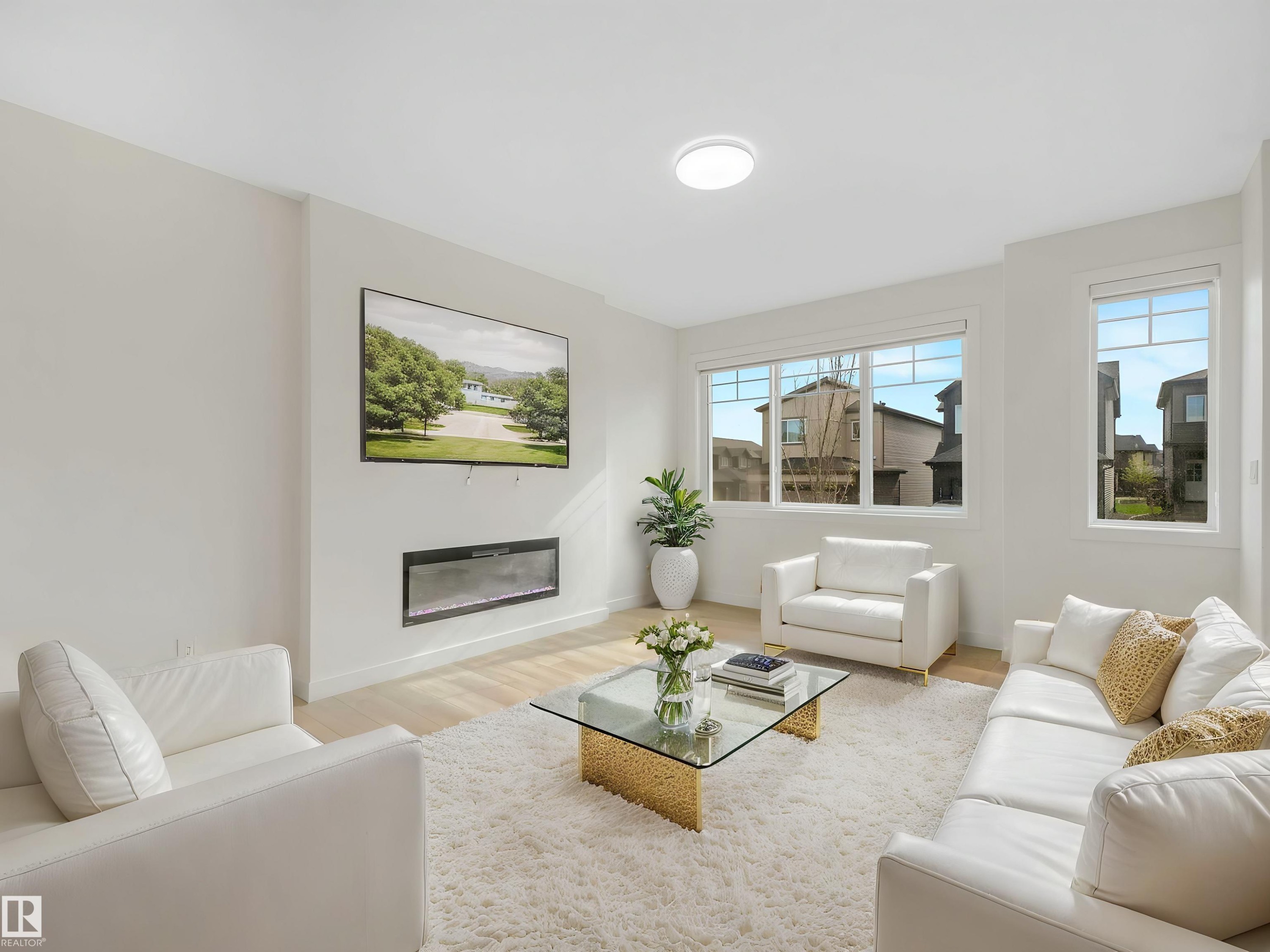Spacious living area featuring light wood-finish flooring, an integrated linear electric fireplace, and large windows - 1518 Siskin Link Link, Edmonton, AB - Indoor Photo Showing Living Room