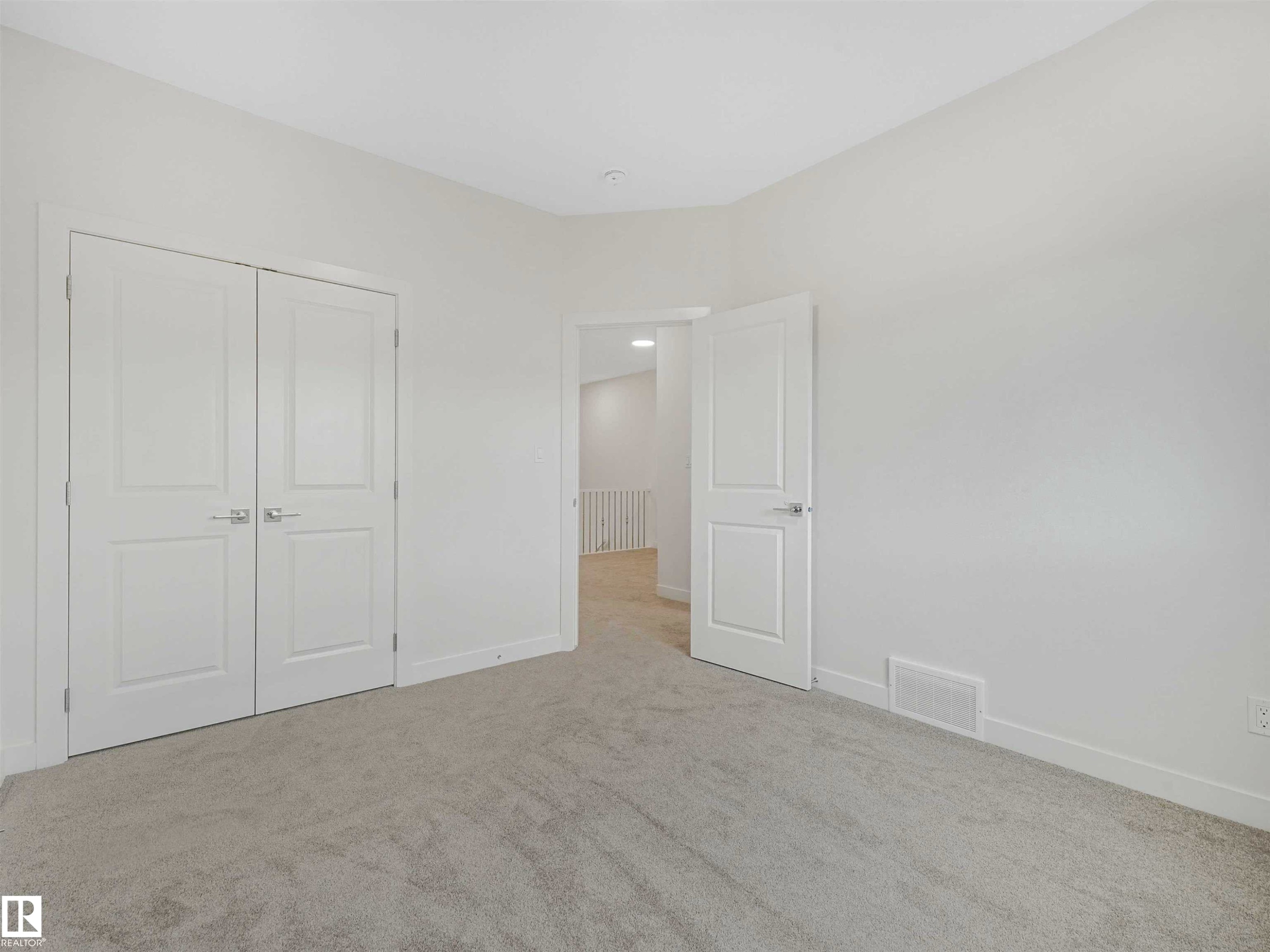 Light gray carpeted room featuring white walls, white trim, and a white six-panel door - 1518 Siskin Link Link, Edmonton, AB - Indoor Photo Showing Other Room