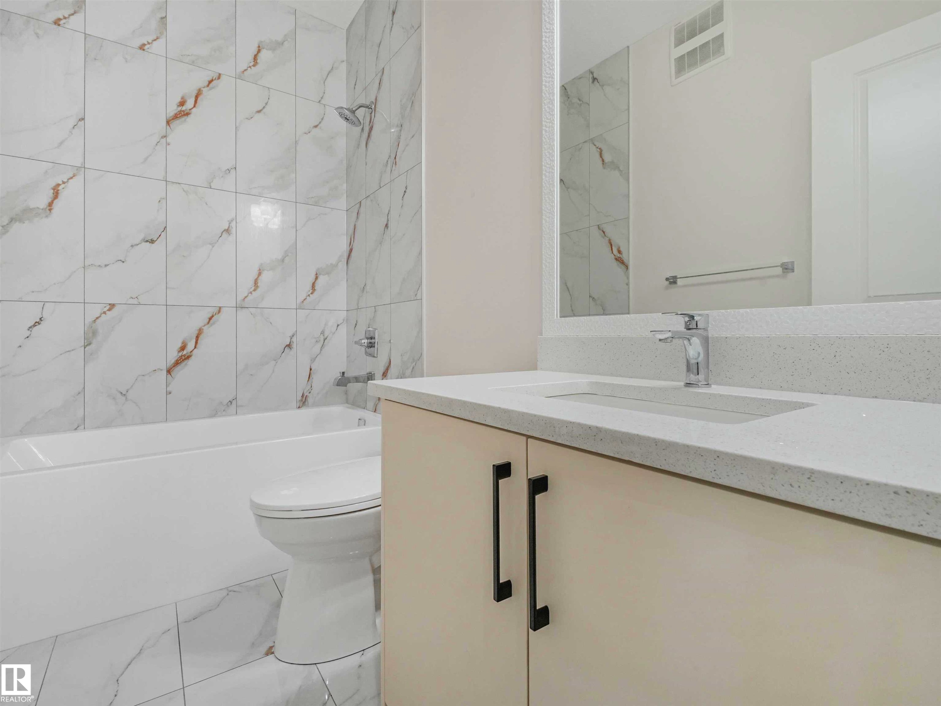 Bathroom featuring a light-toned vanity with integrated sink, chrome faucet, and expansive wall mirror - 1518 Siskin Link Link, Edmonton, AB - Indoor Photo Showing Bathroom