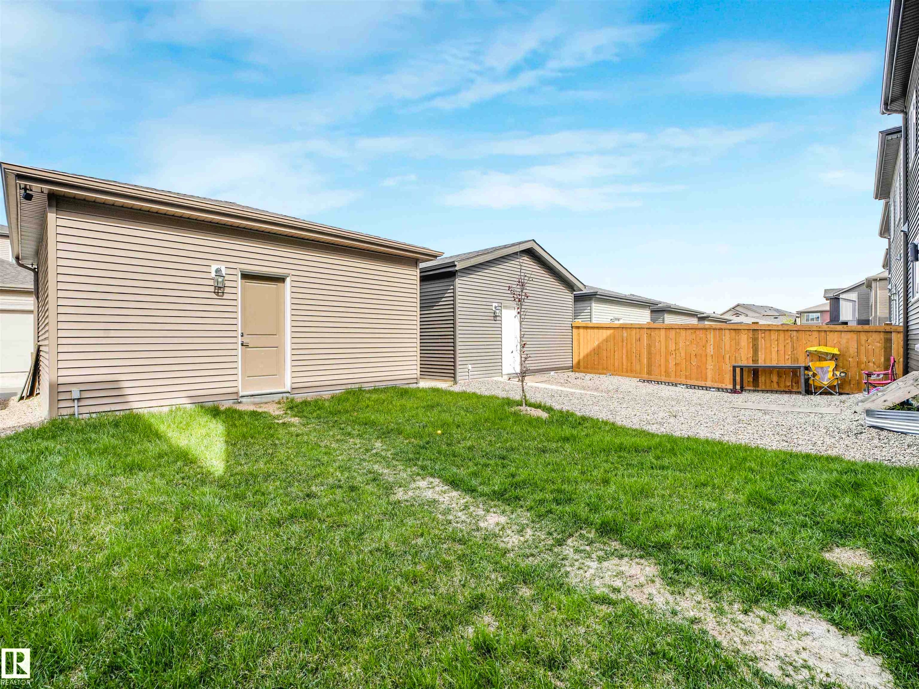 Expansive backyard featuring a manicured lawn, gravel patio, and a wood fence - 1518 Siskin Link Link, Edmonton, AB - Outdoor