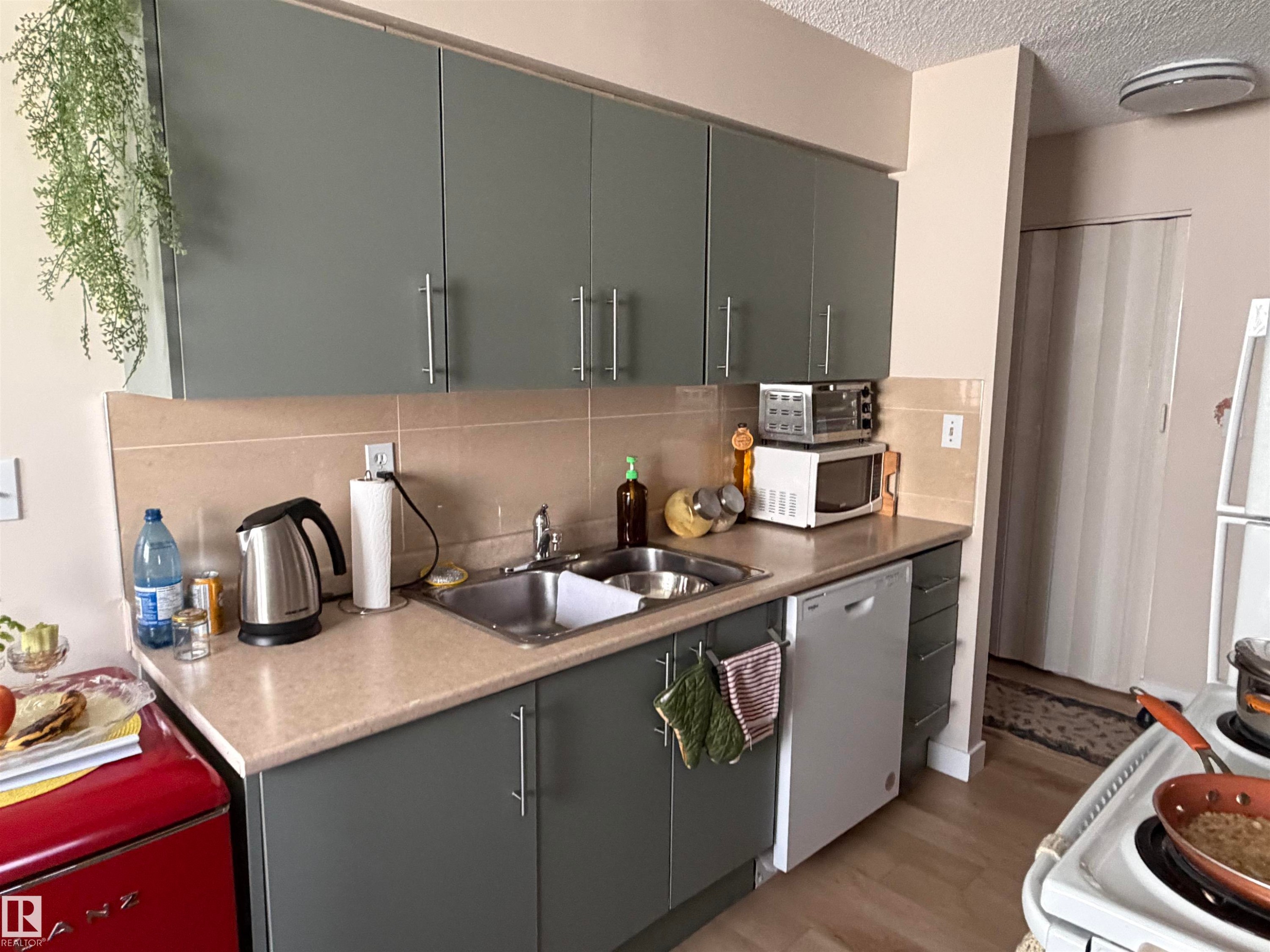 Kitchen featuring grey cabinetry, stainless steel sink, beige countertop, and tile backsplash - 205 10604 110 Avenue Nw, Edmonton, AB - Indoor Photo Showing Kitchen With Double Sink With Upgraded Kitchen