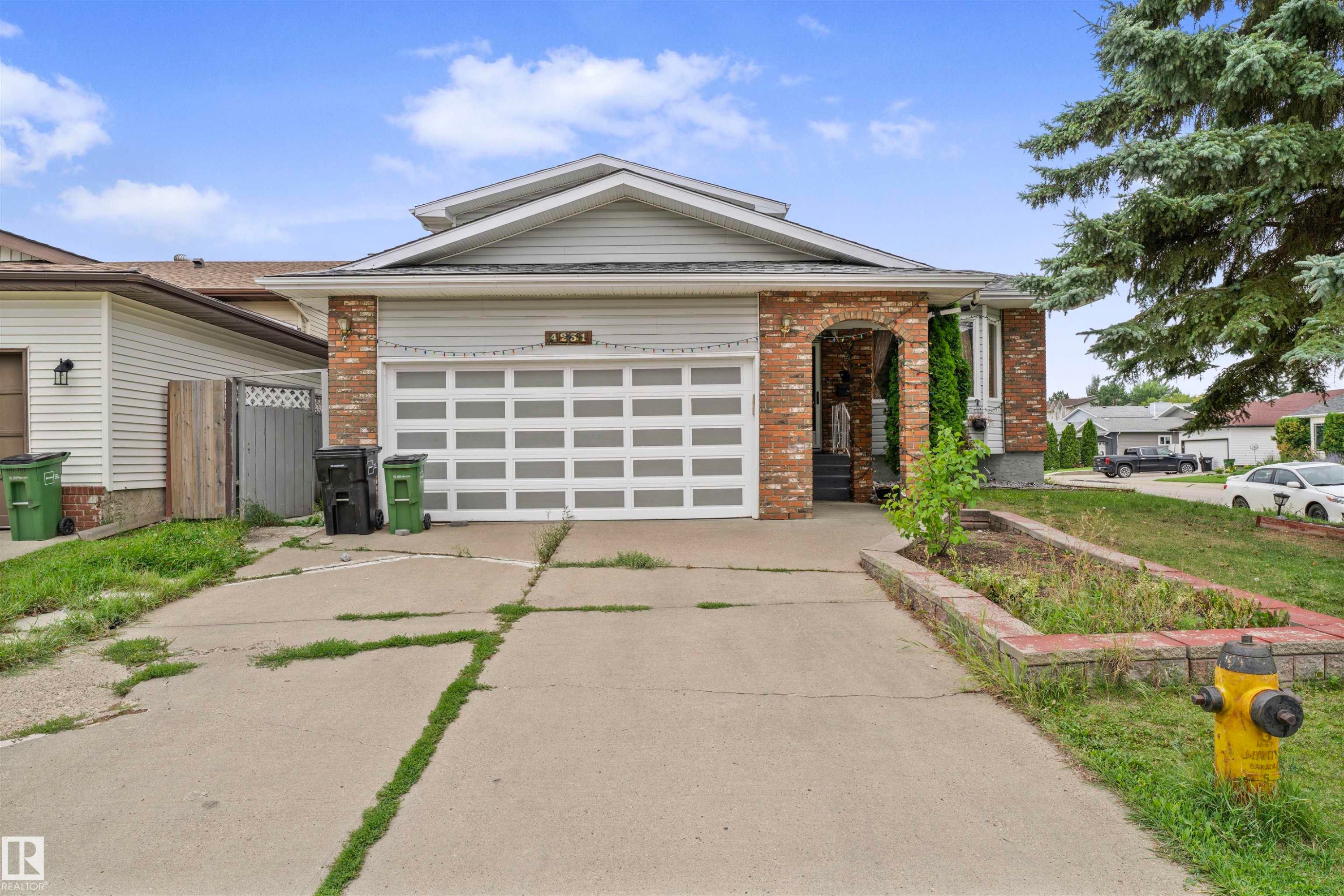 Front exterior featuring brick facade accents, a two-car garage with a panel door, and a concrete driveway - 4231 32 Avenue, Edmonton, AB - Outdoor