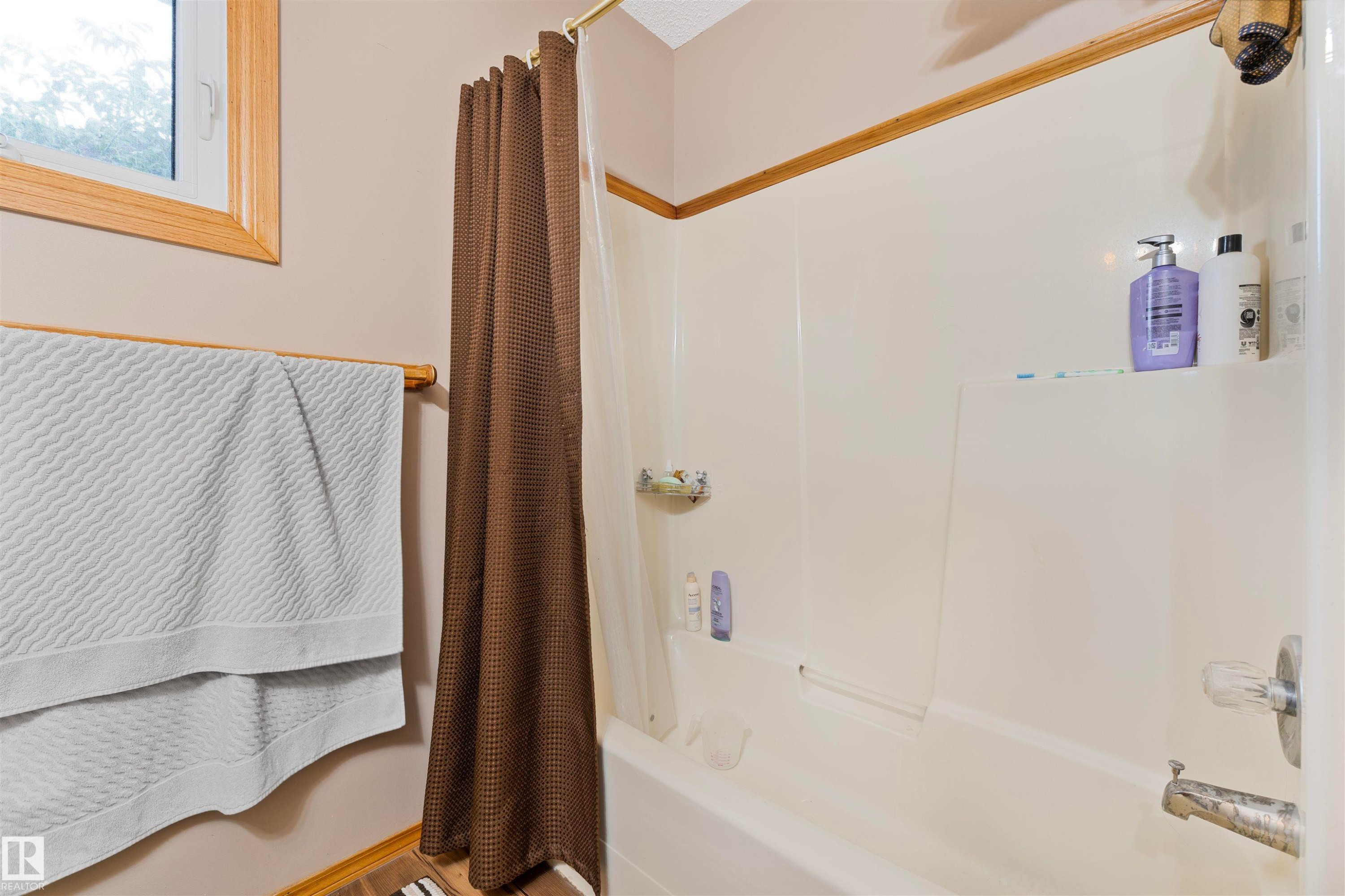 Integrated tub and shower unit with a white acrylic surround - 4231 32 Avenue, Edmonton, AB - Indoor Photo Showing Bathroom