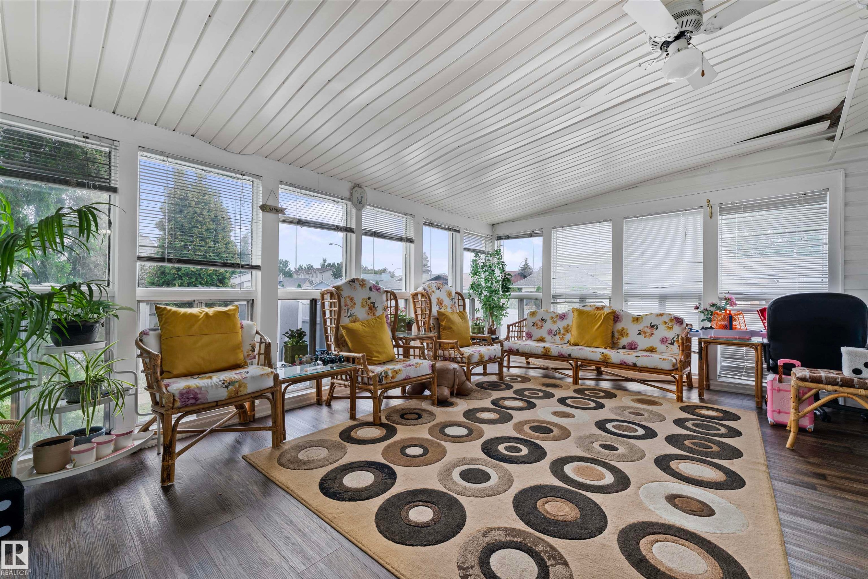 Sunroom featuring a vaulted panel ceiling, numerous windows with blinds, wood-finish flooring, and a ceiling fan - 4231 32 Avenue, Edmonton, AB - With Exterior