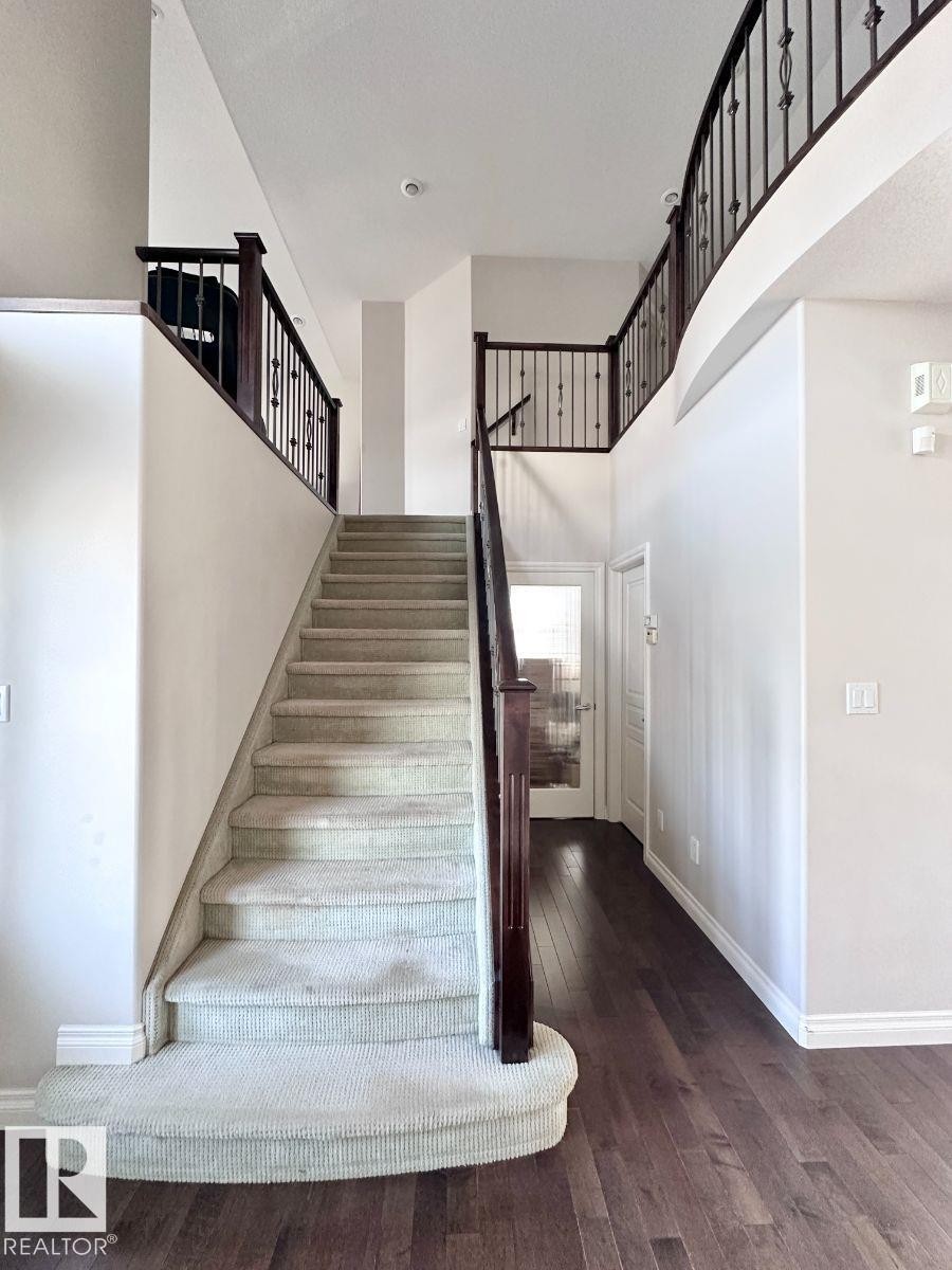 Elegant entryway featuring a grand staircase with carpeted treads and dark wood handrails - 820 Drysdale Run, Edmonton, AB - Indoor Photo Showing Other Room
