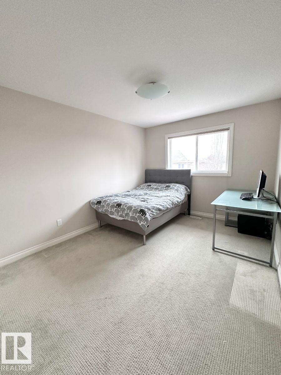 Carpeted room featuring neutral-toned walls, a single window with white trim, and a ceiling-mounted light fixture - 820 Drysdale Run, Edmonton, AB - Indoor Photo Showing Bedroom
