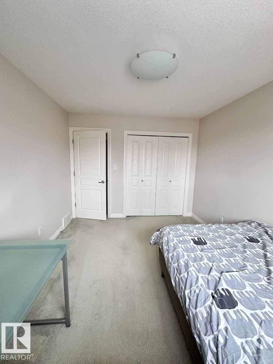 Recessed closet with white bi-fold doors, light-colored carpeting, and a flush-mount ceiling light fixture - 820 Drysdale Run, Edmonton, AB - Indoor Photo Showing Bedroom