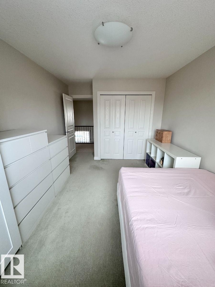 Carpeted room featuring a white bi-fold door closet and a flush mount ceiling light fixture - 820 Drysdale Run, Edmonton, AB - Indoor Photo Showing Bedroom