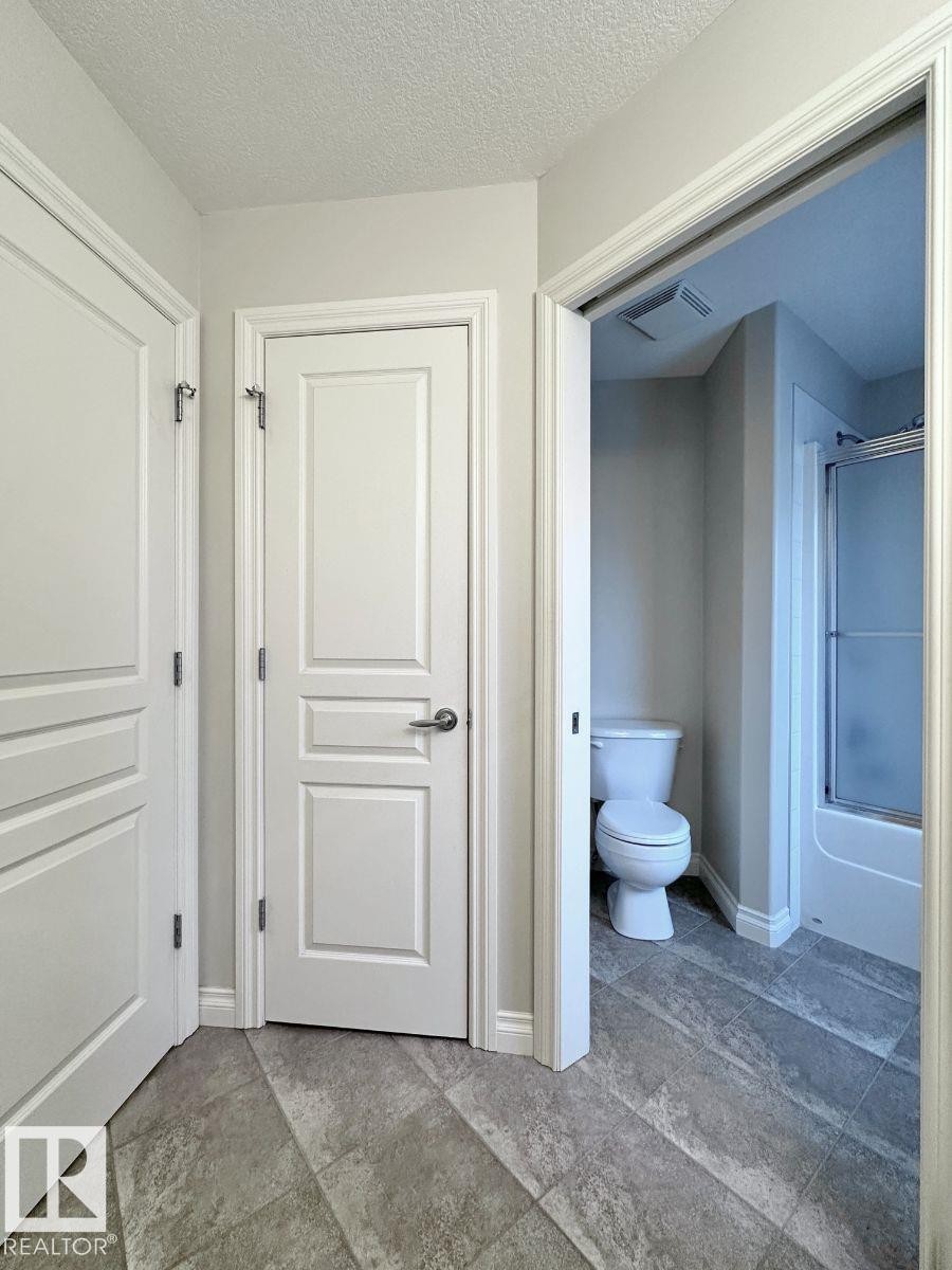 Interior hallway with textured ceiling and two paneled doors, one featuring a polished chrome lever handle - 820 Drysdale Run, Edmonton, AB - Indoor