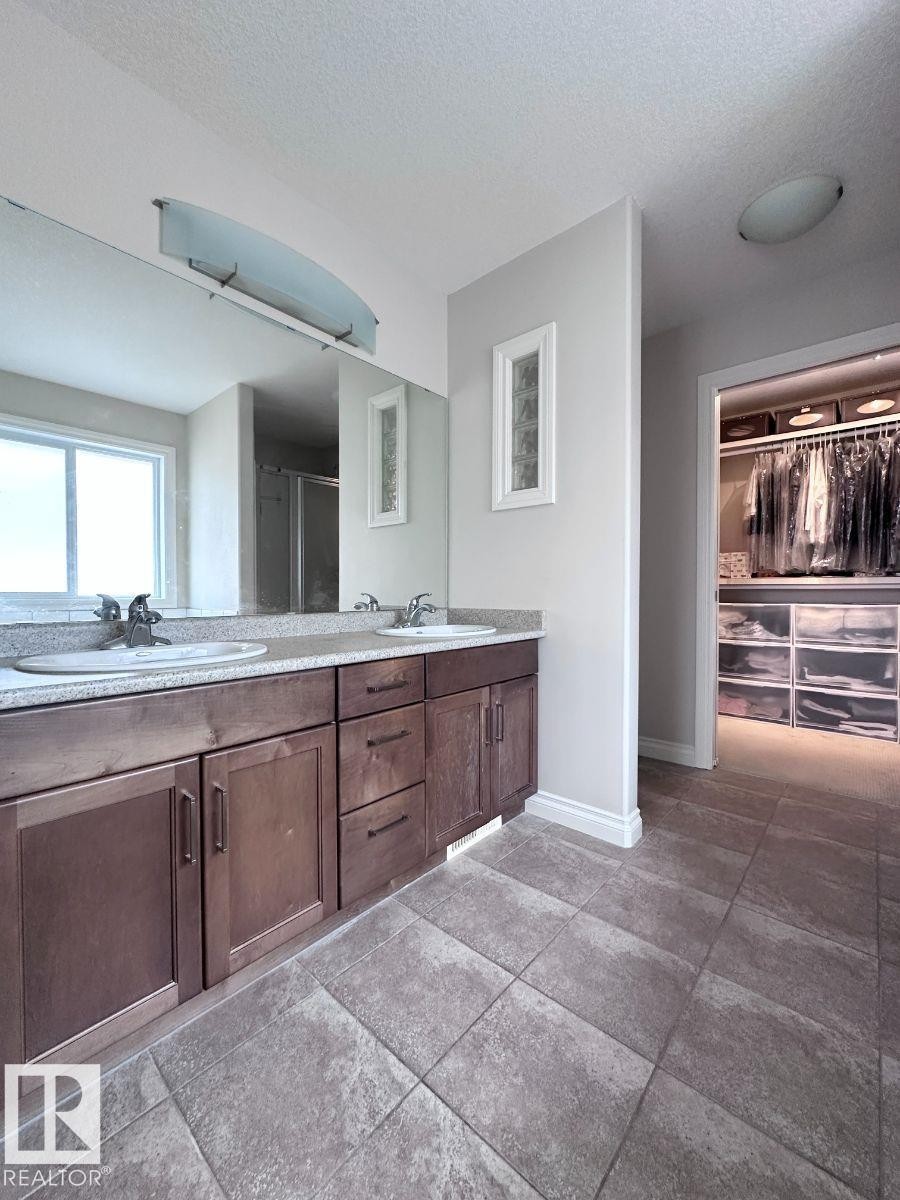 Double vanity with wood-finish cabinetry and light-toned countertops - 820 Drysdale Run, Edmonton, AB - Indoor Photo Showing Bathroom