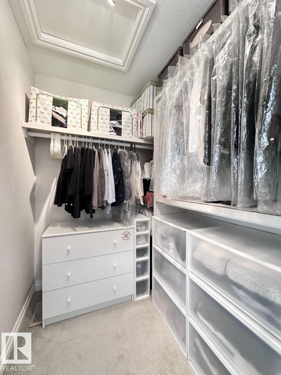 Custom closet system featuring built-in shelving, hanging rods, and integrated drawer storage - 820 Drysdale Run, Edmonton, AB - Indoor With Storage