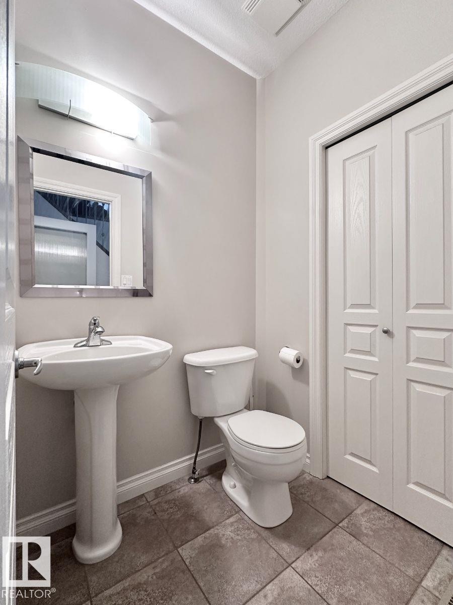 Pedestal sink with chrome faucet, complemented by a rectangular framed mirror and modern wall-mounted lighting - 820 Drysdale Run, Edmonton, AB - Indoor Photo Showing Bathroom