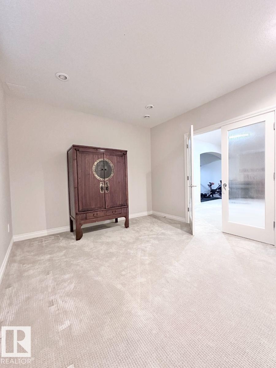 Recessed lighting illuminates a carpeted space, featuring light neutral wall tones and white baseboards - 820 Drysdale Run, Edmonton, AB - Indoor