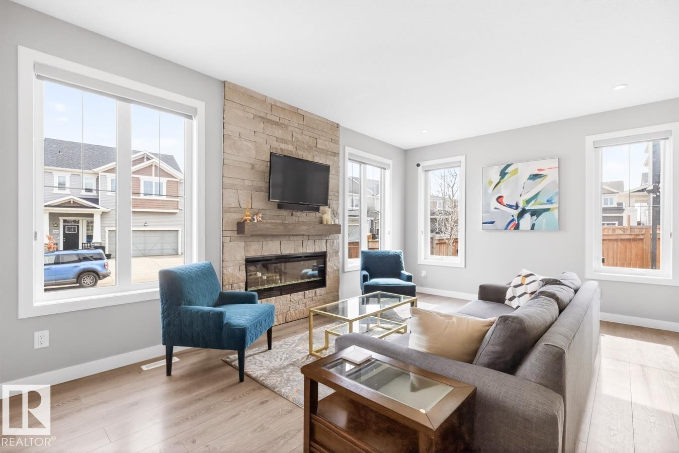 Spacious Living Room with Ample Windows allowing tons of Natural Light, Fireplace, and Open Concept to the Kitchen and Dining Room Space. - 20023 17A Avenue, Edmonton, AB - Indoor Photo Showing Living Room With Fireplace