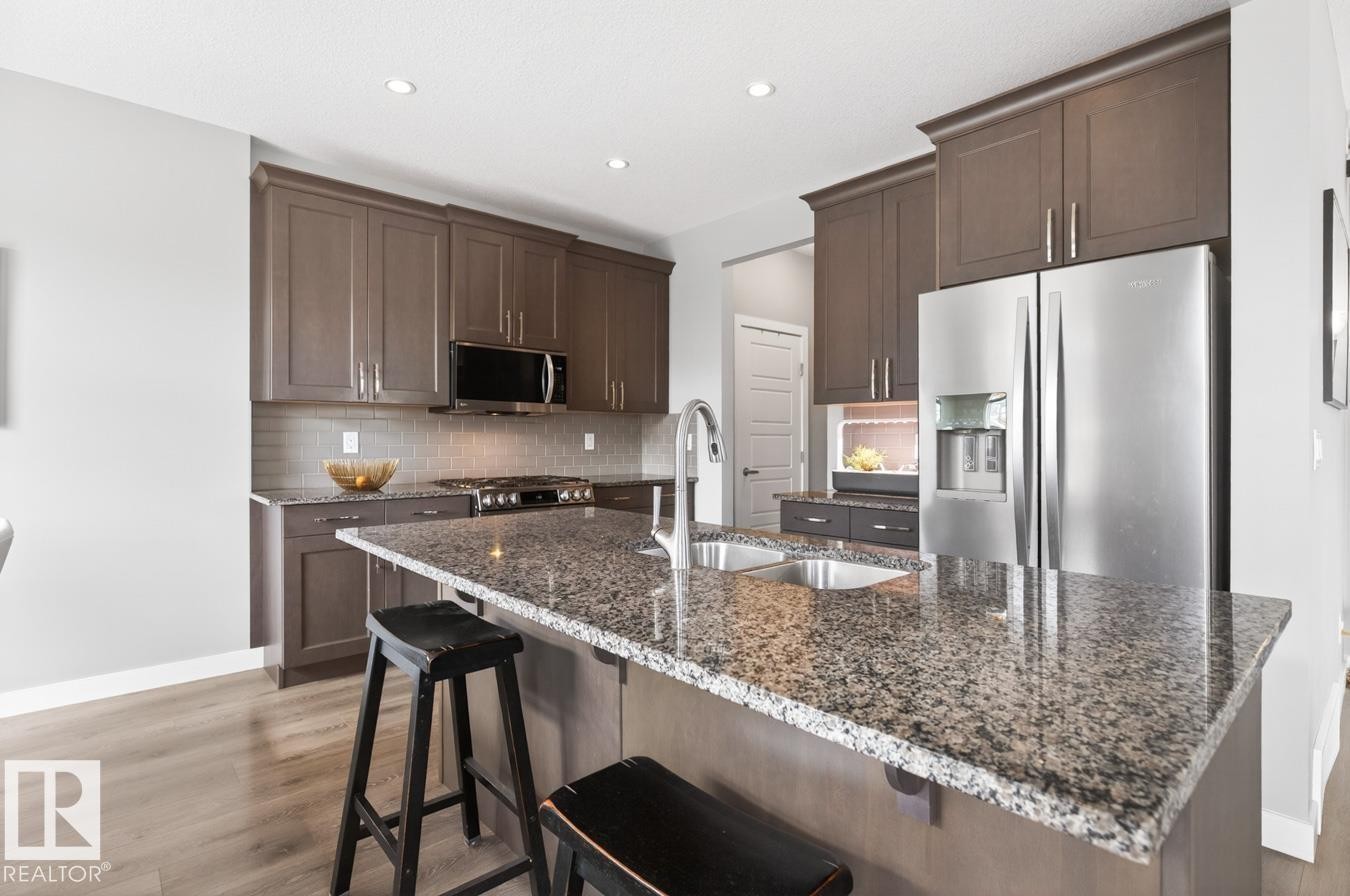 Stylish Kitchen featuring Quartz Counters, Stainless Steel Appliances (Bosh Dishwasher, Whirlpool Refrigerator, LG GAS Stove, LG Microwave Hood Fan), Subway Tile Backsplash, and plenty of Counter and Cabinet Space. - 20023 17A Avenue, Edmonton, AB - Indoor Photo Showing Kitchen With Double Sink With Upgraded Kitchen