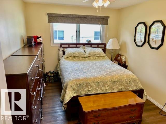 Bedroom featuring wood-finish flooring, a window with a roller shade, and a ceiling fan - 4805 53Ave, Willingdon, AB - Indoor Photo Showing Bedroom