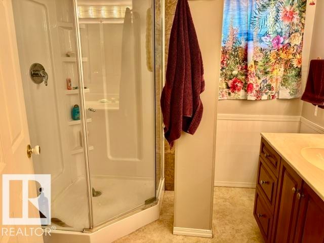 Corner shower enclosure with clear glass panels, a single chrome fixture, and integrated shelving - 4805 53Ave, Willingdon, AB - Indoor Photo Showing Bathroom