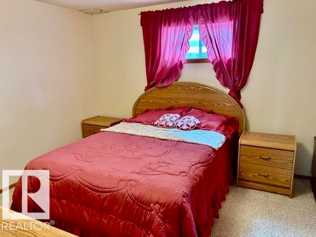 Bedroom featuring neutral wall paint, carpet flooring, and a window with a valance - 4805 53Ave, Willingdon, AB - Indoor Photo Showing Bedroom