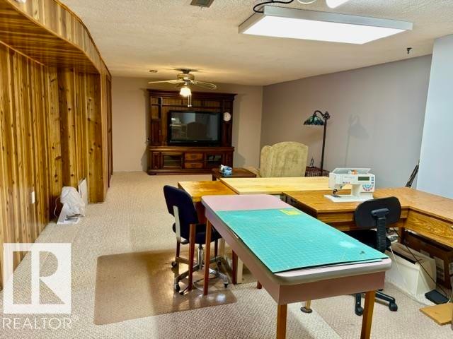 Wood-paneled accent wall, neutral carpeting, recessed ceiling lighting, and a ceiling fan - 4805 53Ave, Willingdon, AB - Indoor
