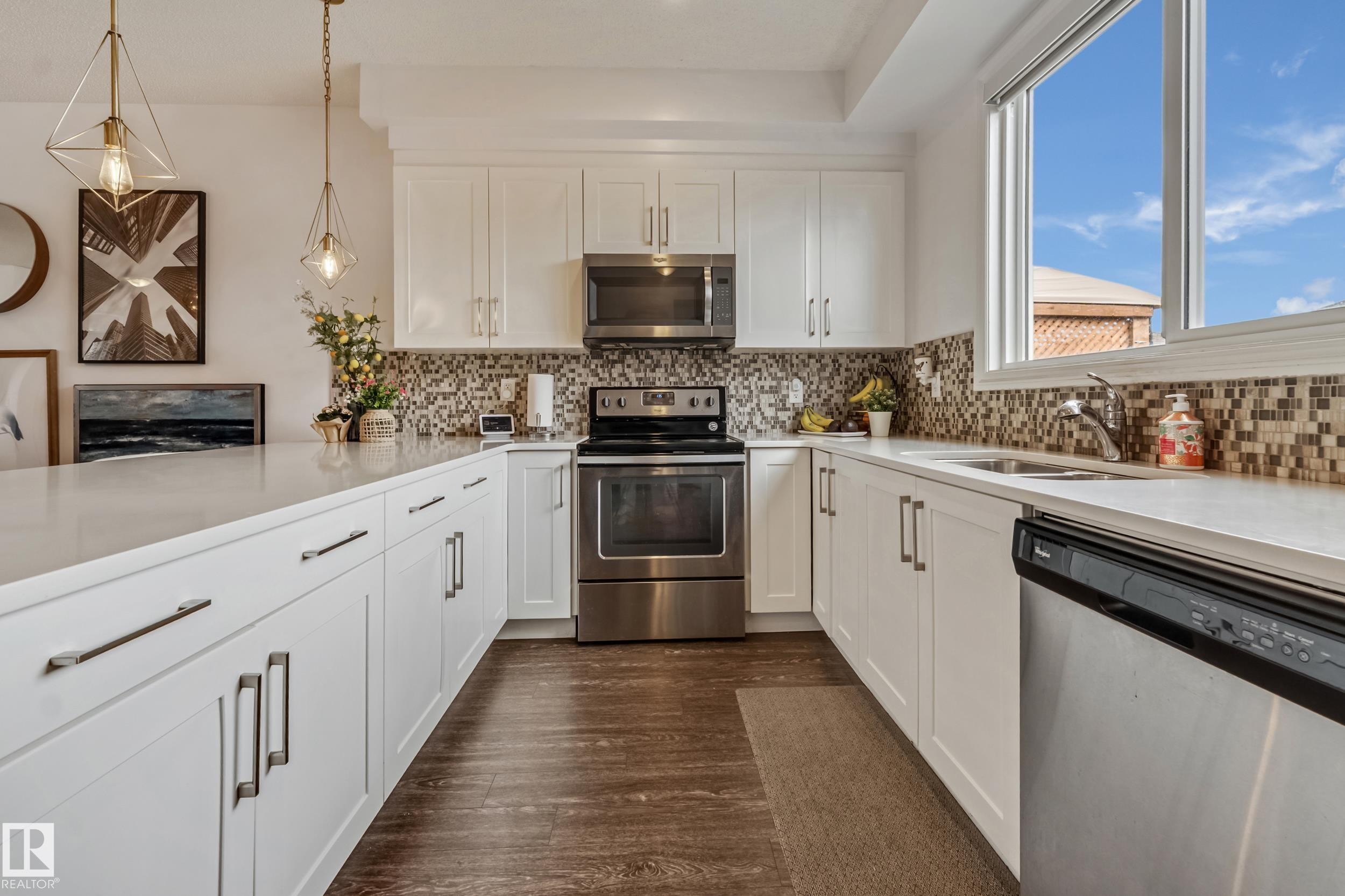 Contemporary kitchen featuring white cabinetry, light-toned countertops, and a mosaic tile backsplash - 8131 Chappelle Way, Edmonton, AB - Indoor Photo Showing Kitchen With Double Sink
